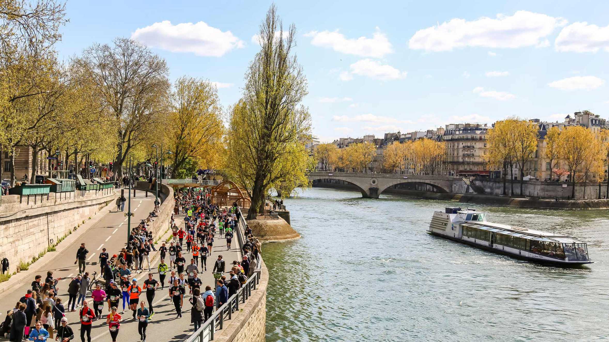 A crowd of runners making their way along the banks of the River Seine.