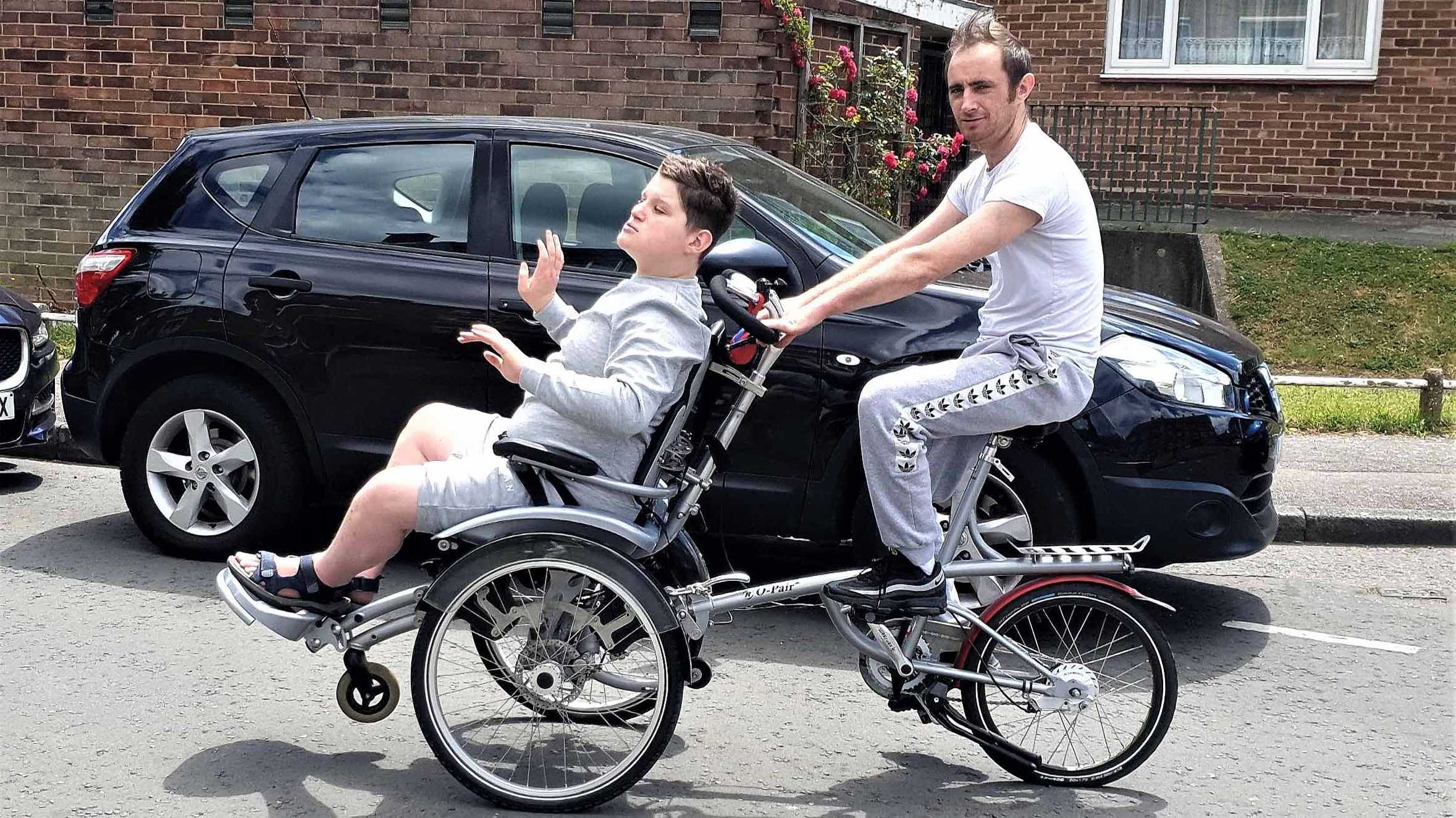 Eric being pedalled along the road on his specially adapted bike.