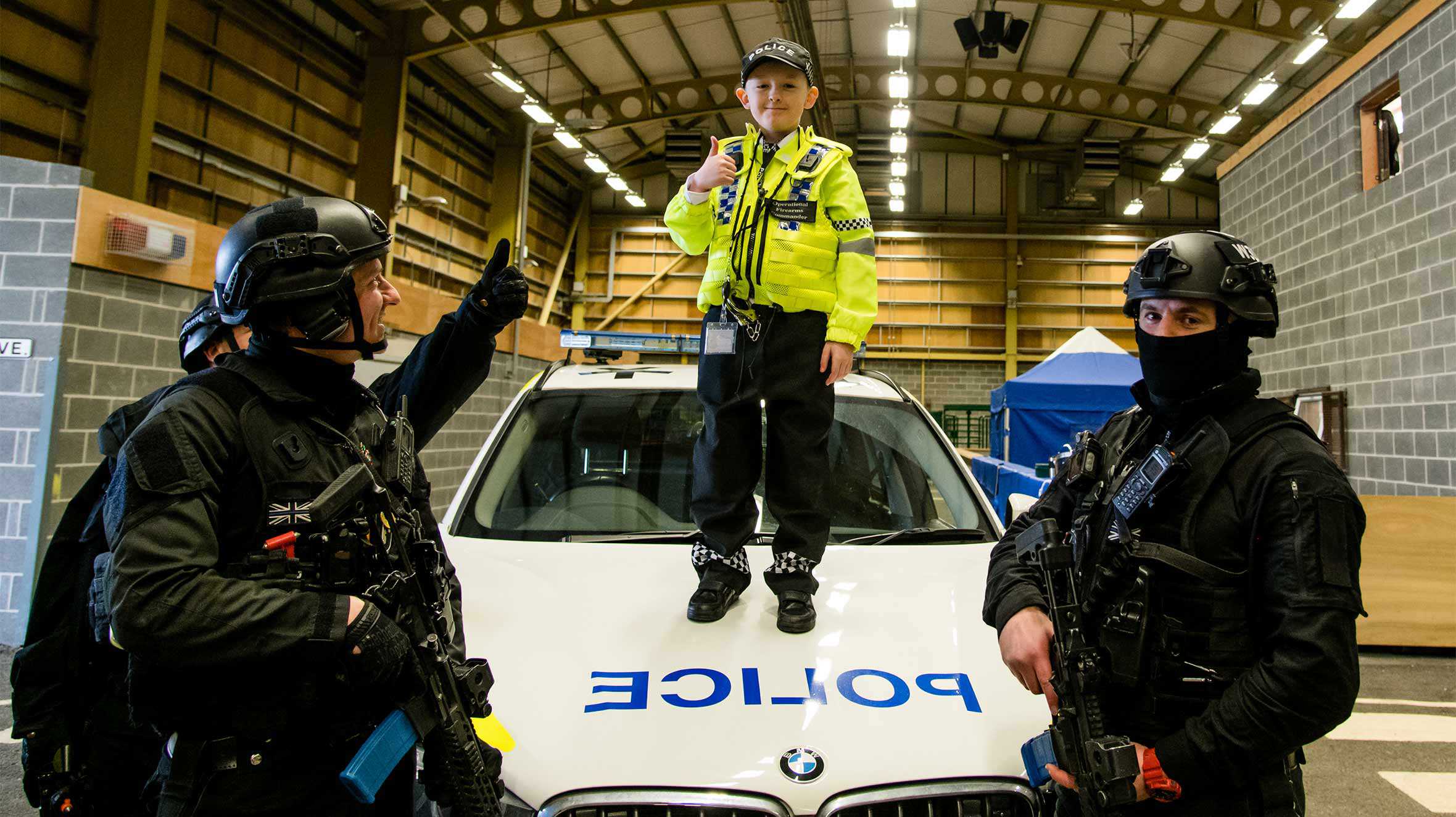 Allan standing on the bonnet of a police car with armed response officers.
