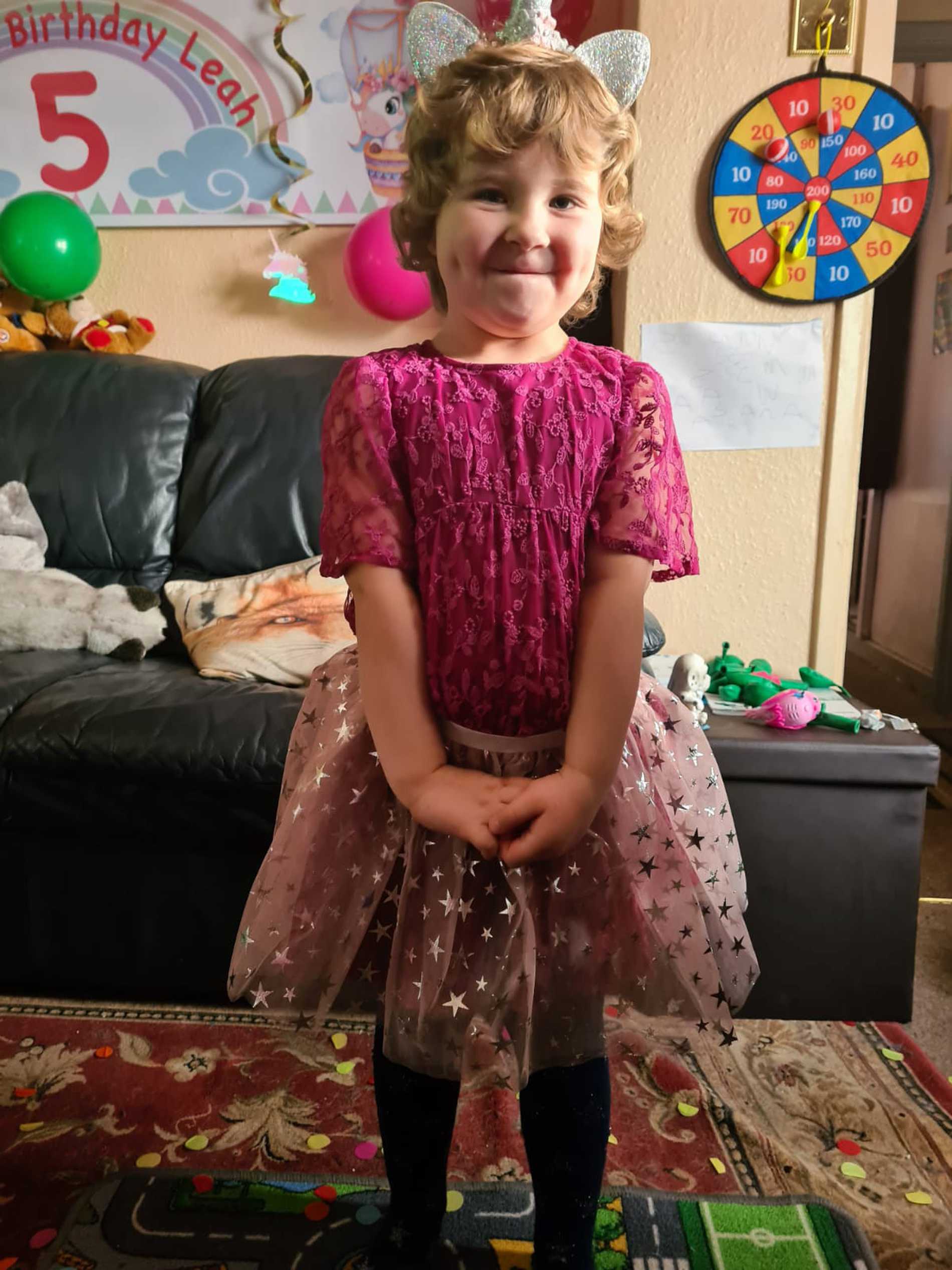 A smiling Leah wearing her cerise party dress.