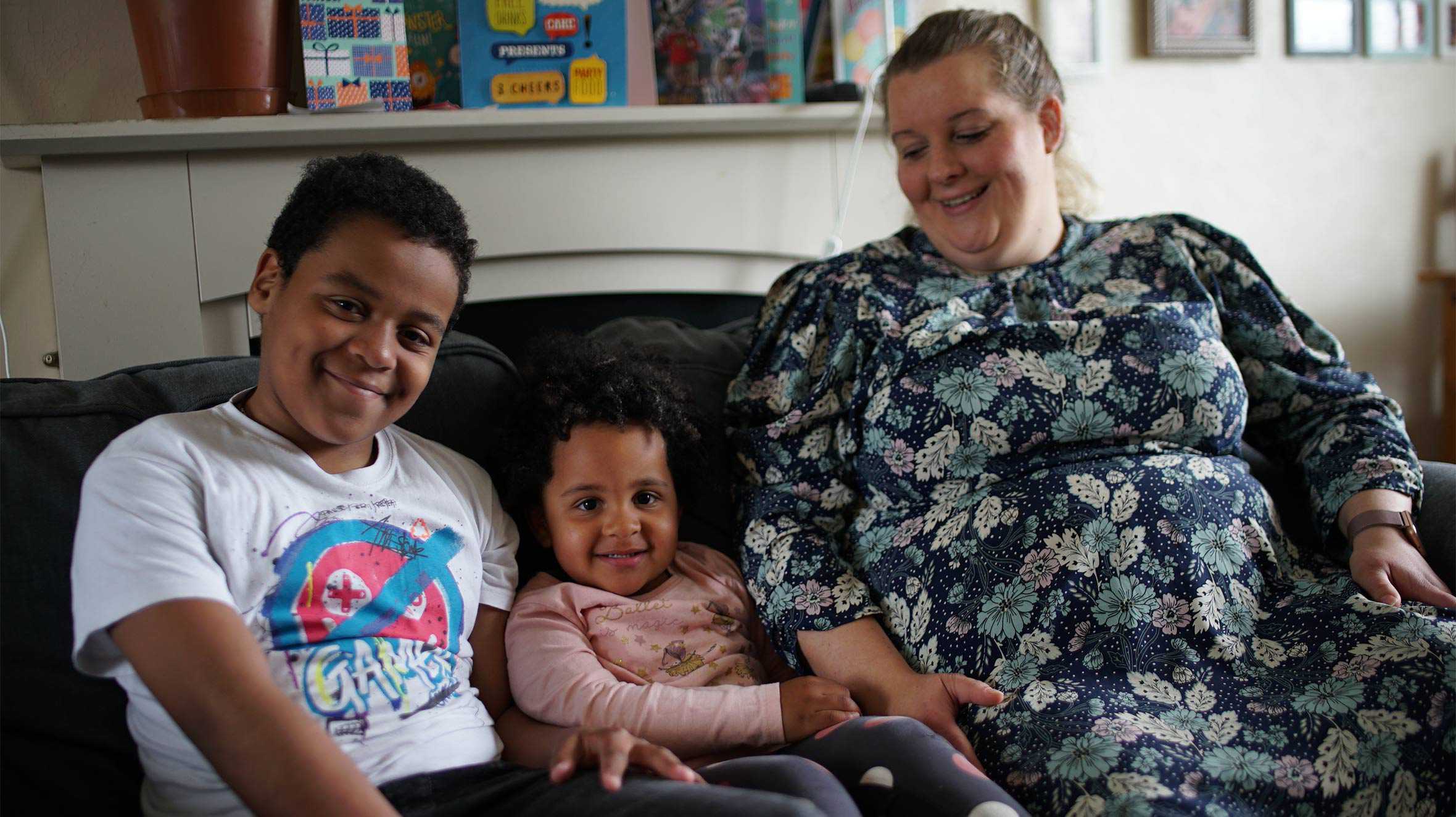 Lukasz, sitting on the sofa with his mum and sister.