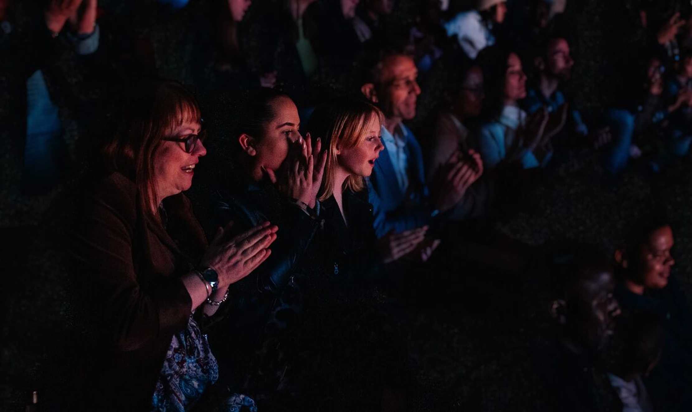 Faith and her two family members are sat in the dark audience, clapping at the end of The Lion King.
