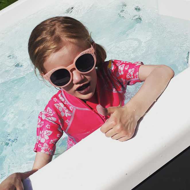 Ava wearing her sunglasses and a pink swimming costume in the hot tub.