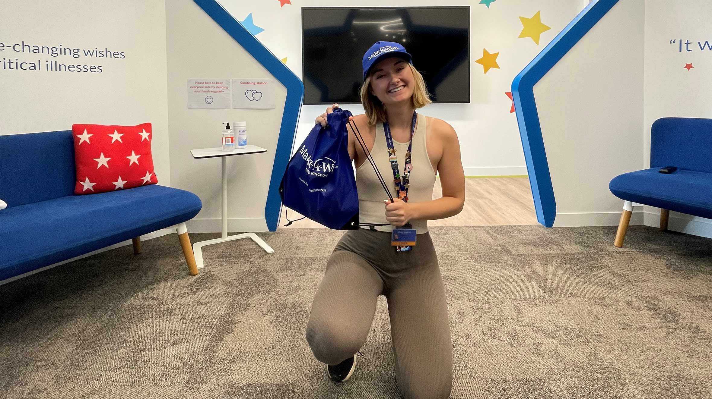 Wishgranter, Micky kneeling in front of the Make-A-Wish star entrance, holding one of our goodie bags.