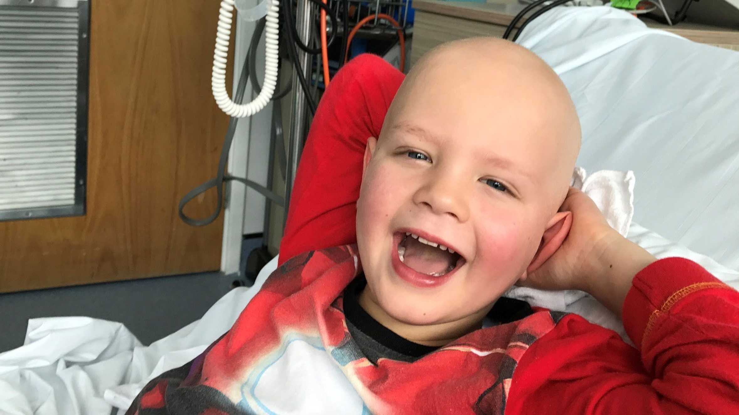 Brave wish child, Alex smiling in his hospital bed while receiving treatment.