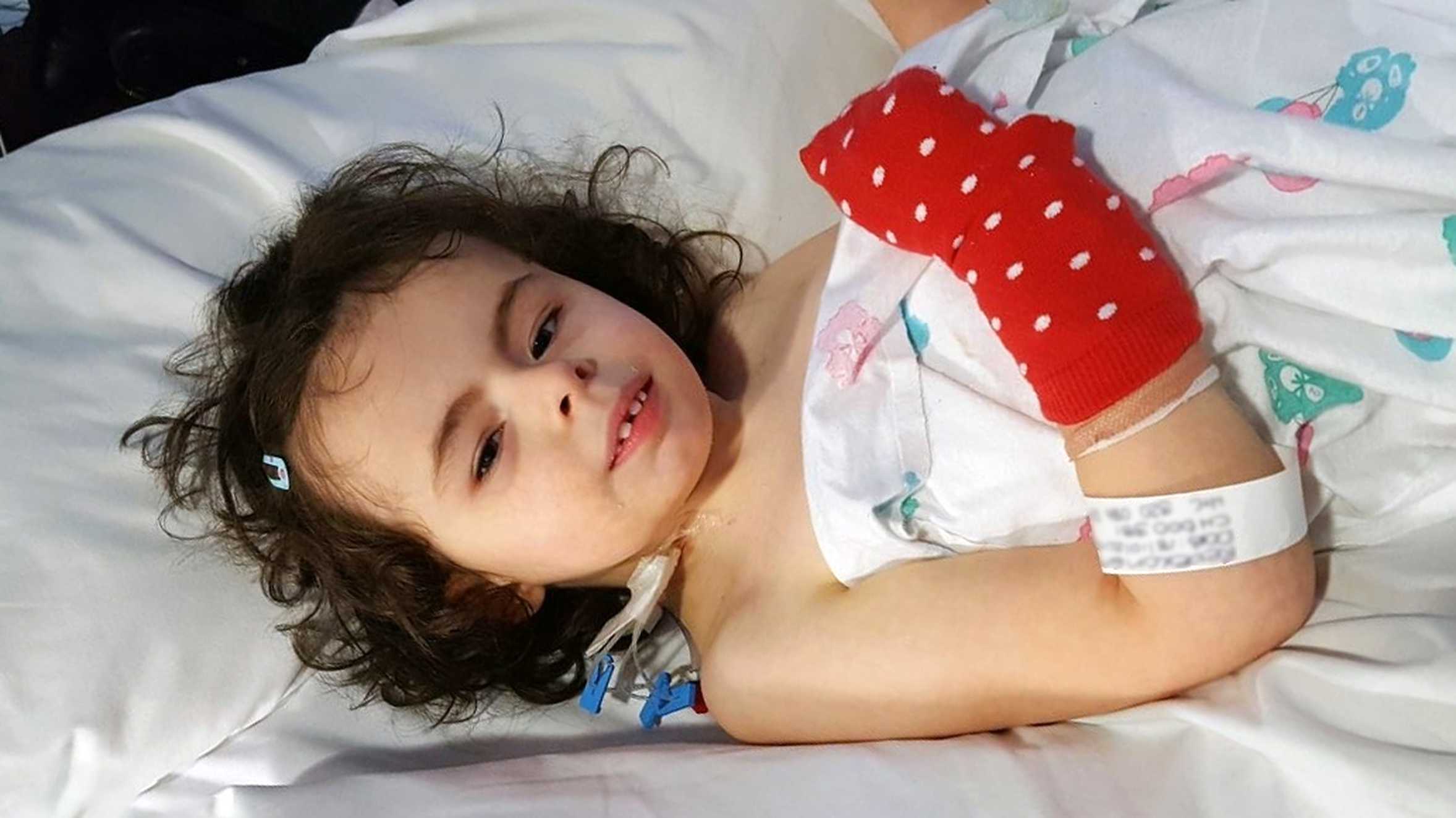 A brave Rebekah smiling in her hospital bed during treatment for her condition.