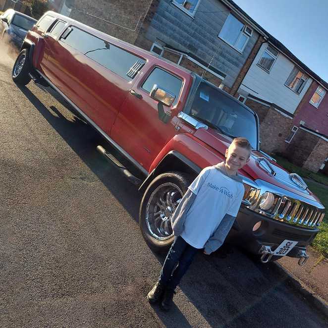 Alfie standing in front of the red Hummer limo during his wish.