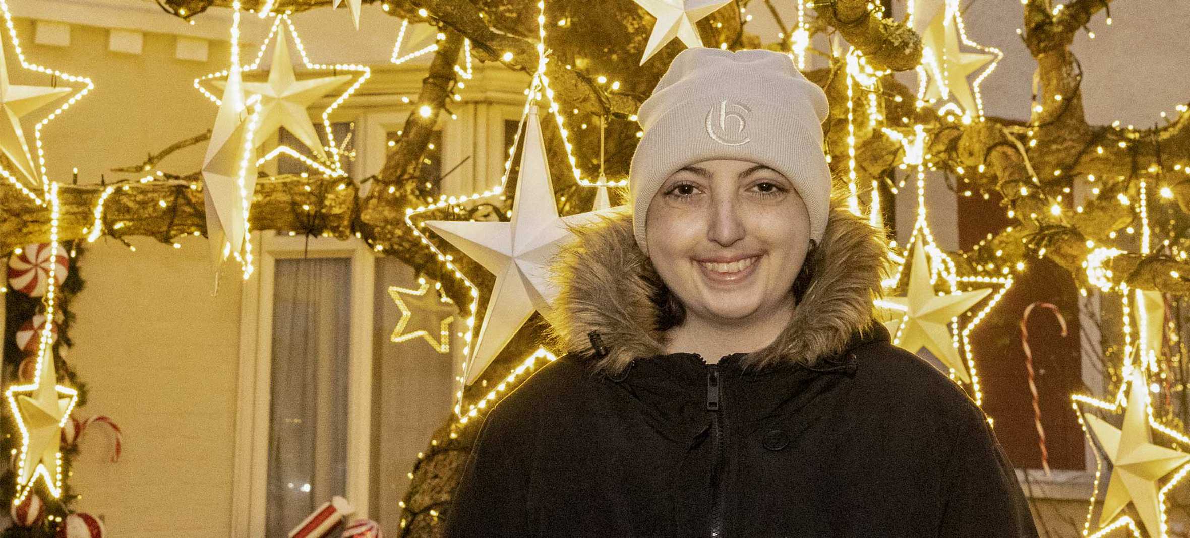 Ellie standing in front of the brightly lit wish tree, outside her house - Image © Phil Harris, Daily Mirror.