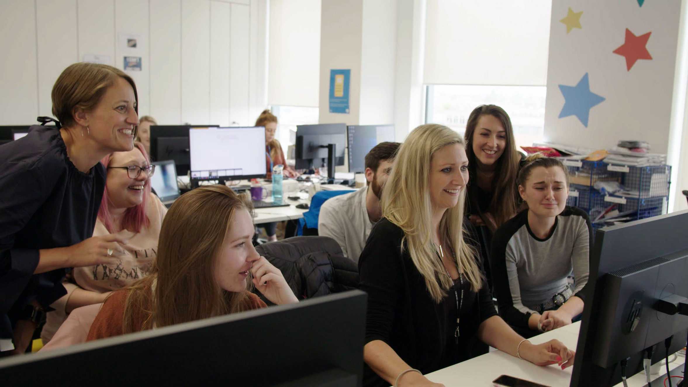 A group of Wishgranters gathered round a computer to read a thank you message from a wish family.