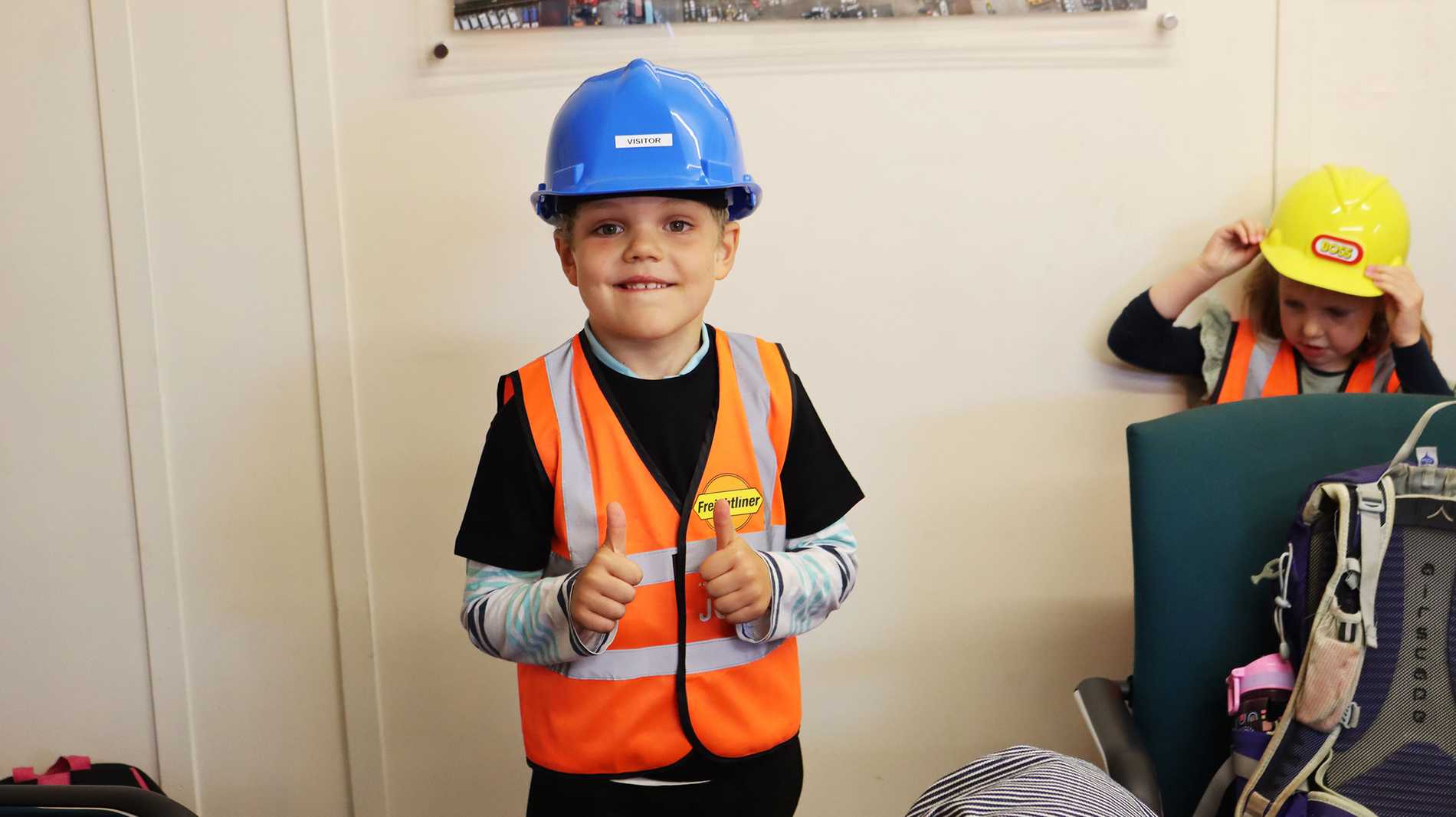 Josiah, wearing a high vis vest and hard hat, giving two thumbs up.