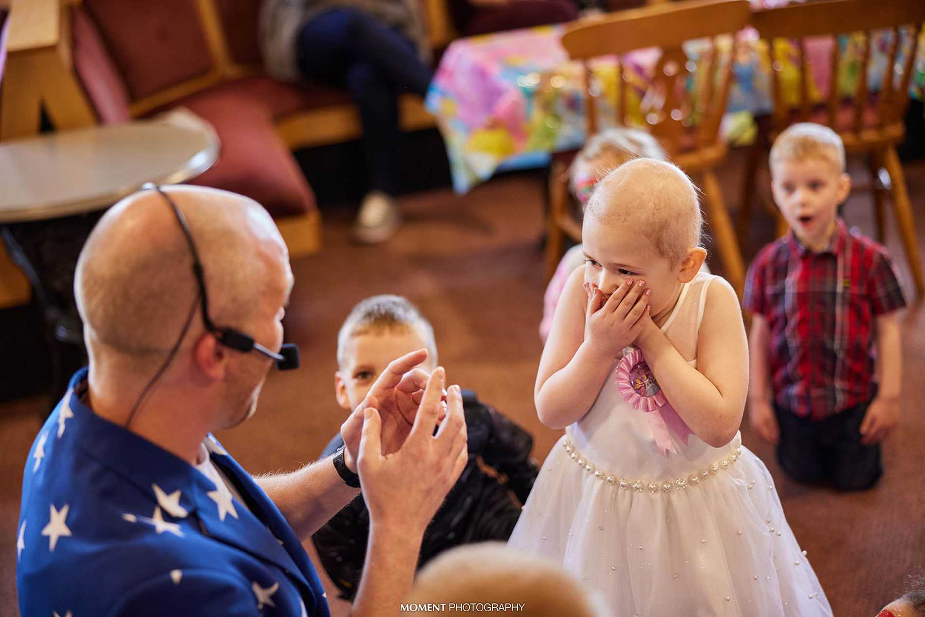 An excited Ryleigh with her hands over her mouth as she watches the entertainer.