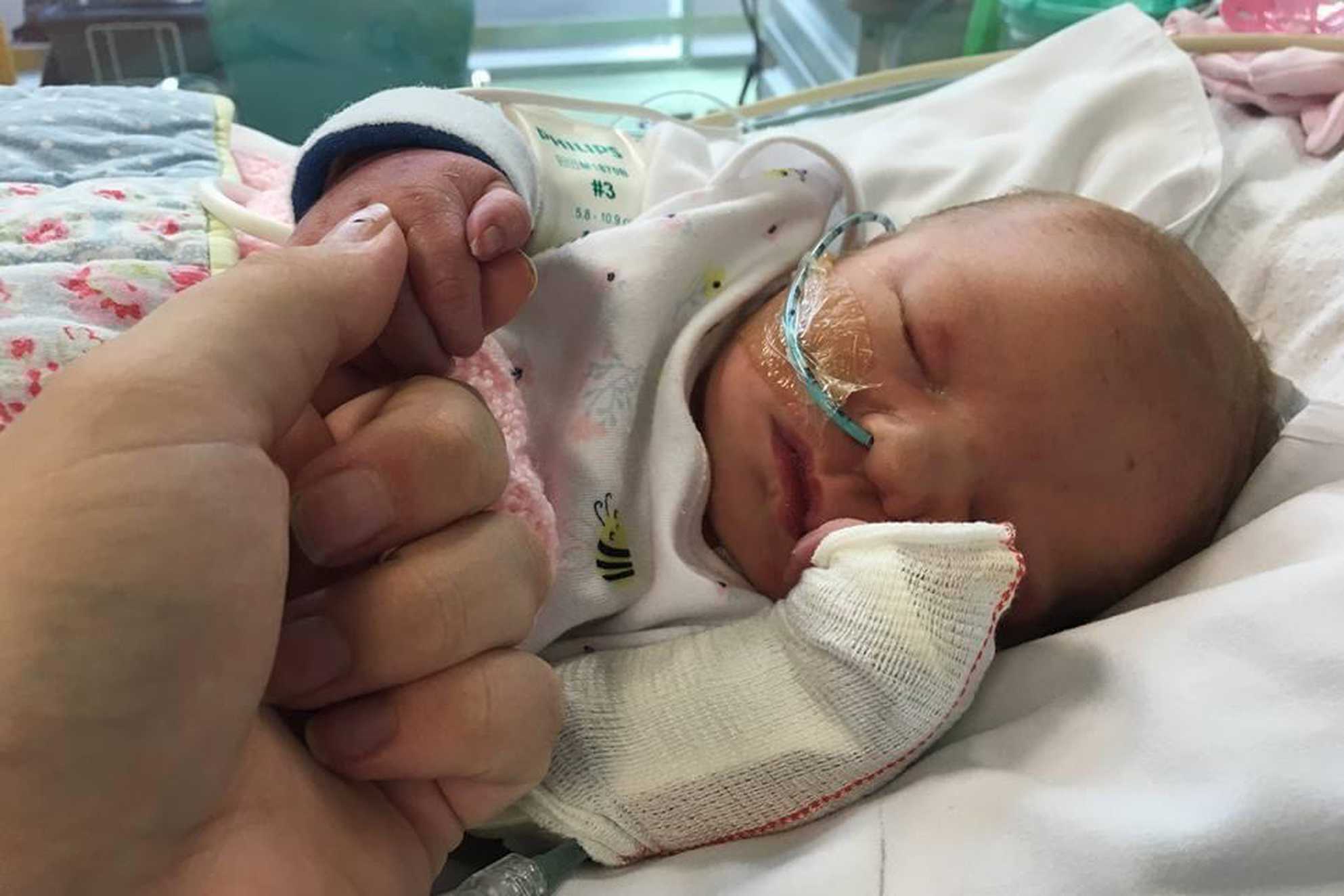 Charlotte in hospital as a baby, holding her mum's hand.