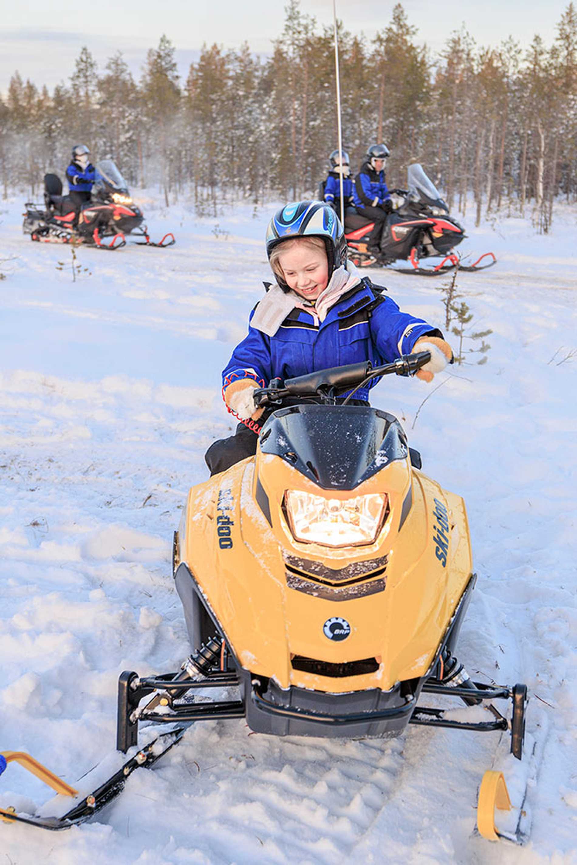 Alice riding a yellow snowmobile during her trip to Lapland.