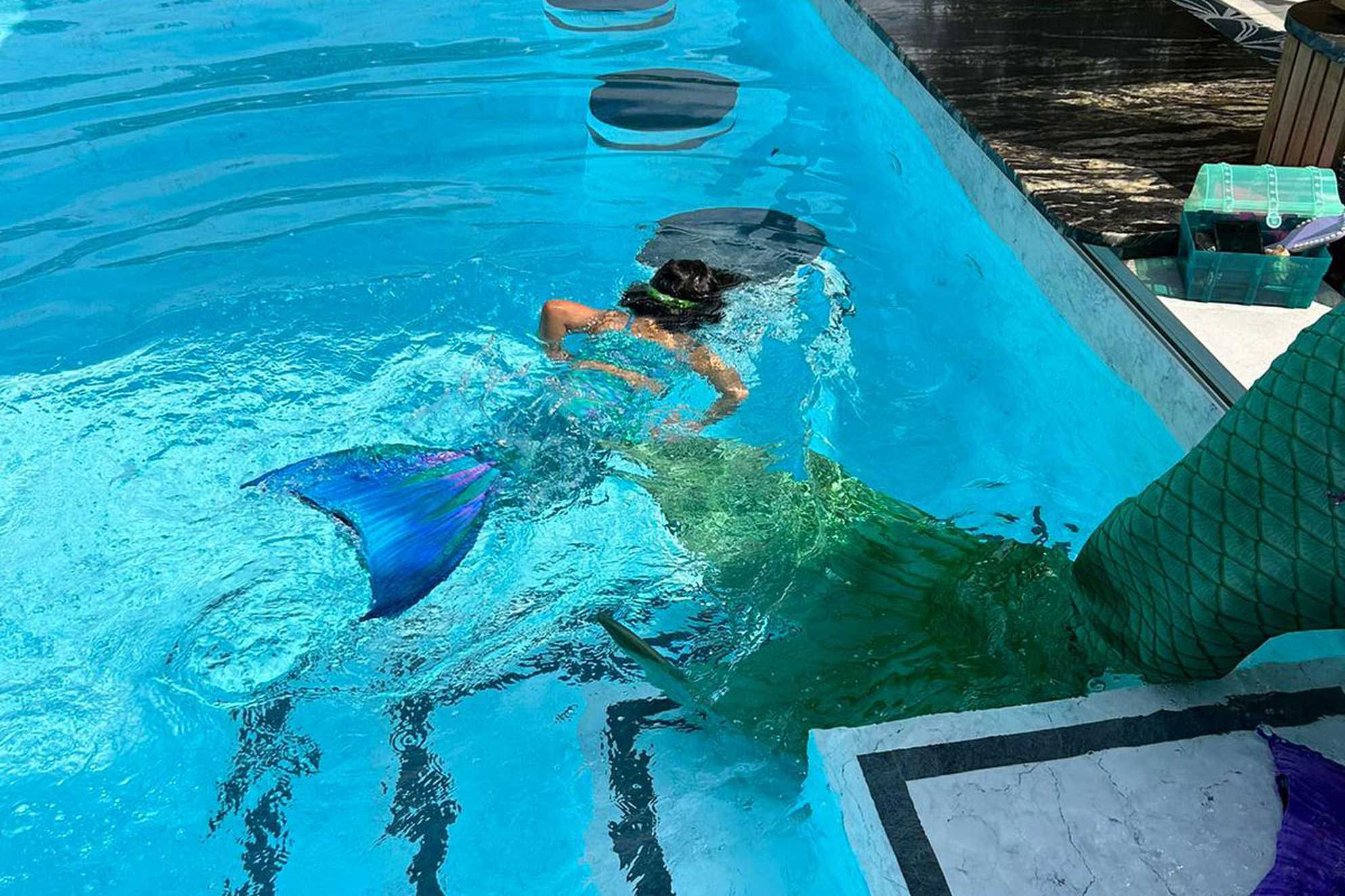 Lila swimming in the outdoor pool while wearing her Mermaid tail.