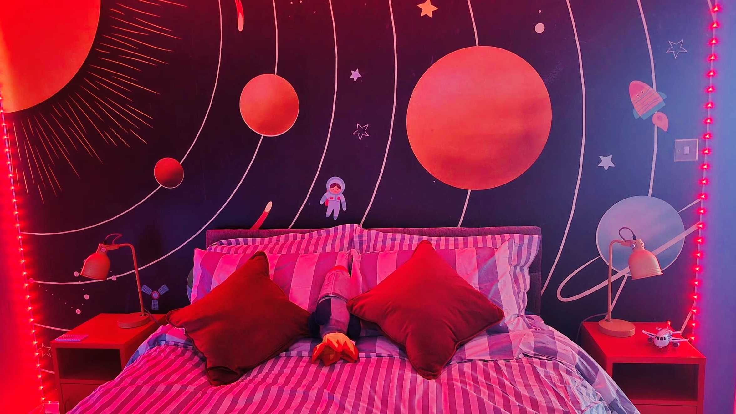 A solar system background wallpaper above Noor's bed