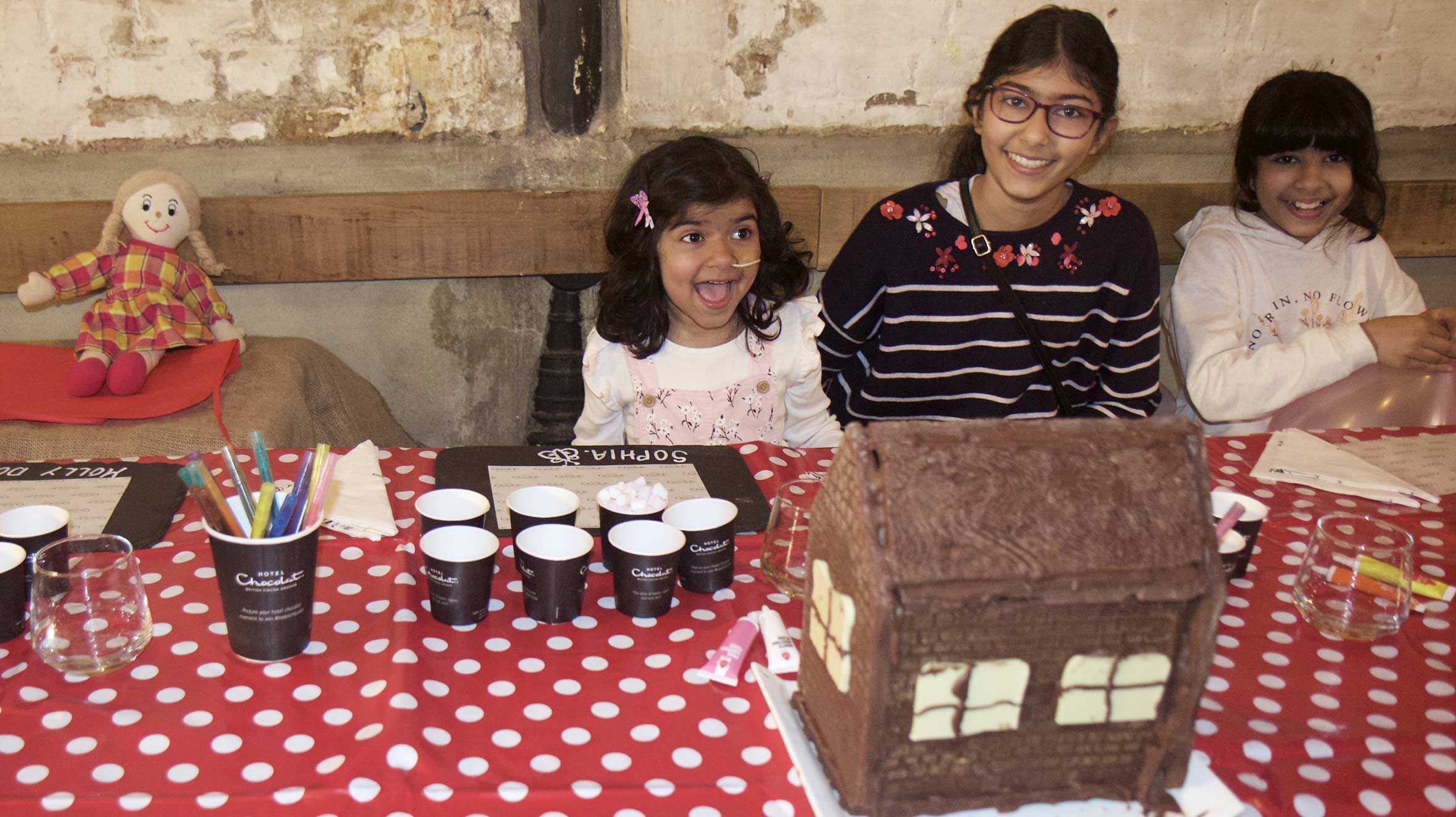 Sophia and her sisters sitting at a table full of goodies during her wish.