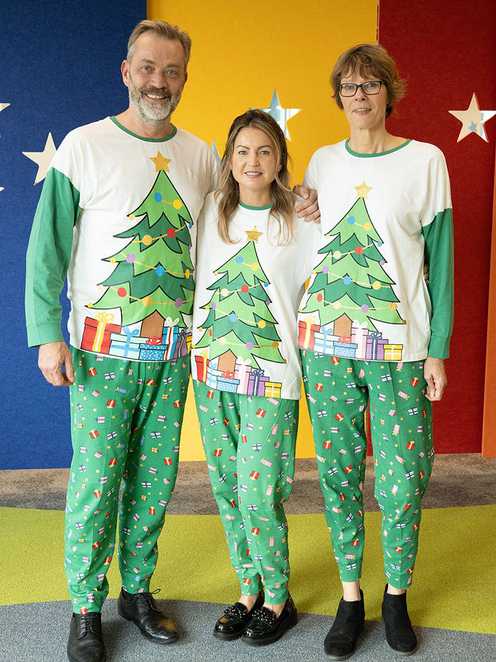 Three of the Make-A-Wish team modelling Peacocks' 2023 Christmas pyjamas, featuring a Christmas tree design.