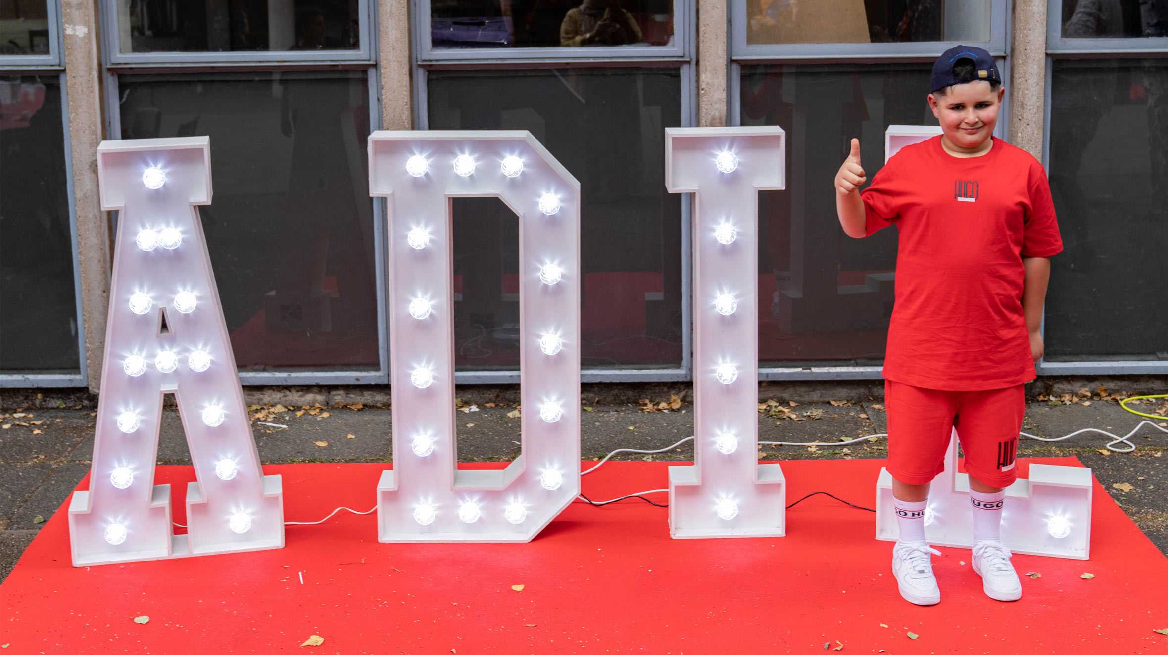 Wish child, Adil standing in front of his name spelled out in giant light up letters.