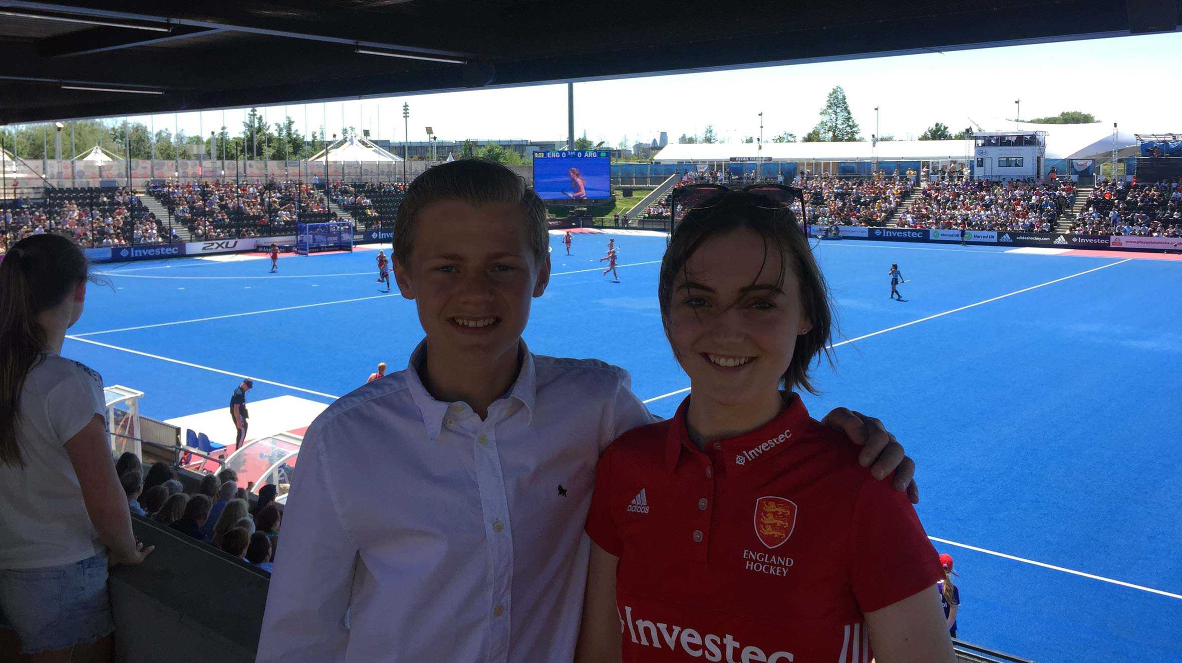 Lucy and her brother in the stand at the England vs Argentina match, with the pitch in the background.