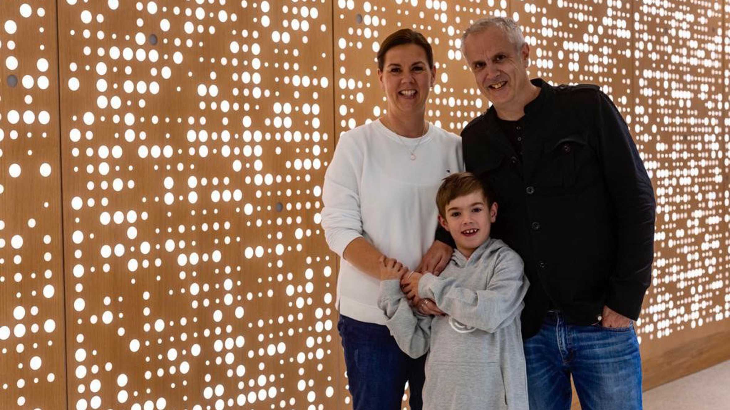 Stanley and his parents standing in front of a wall of lights.