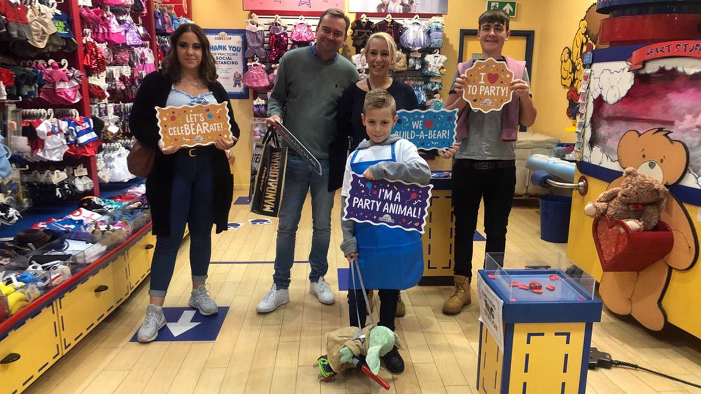 Alfie and his family posing with signs in one of the shops during his shopping spree.
