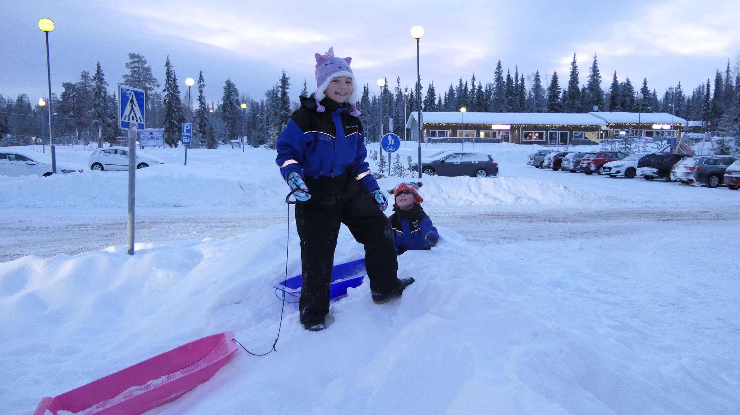 Wish child, Gracie and brother, Oli playing in the snow with sledges during their trip to Lapland.