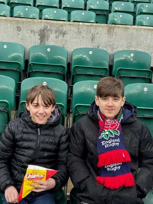 Seth and his brother smile while sat in their seats at Twickenham