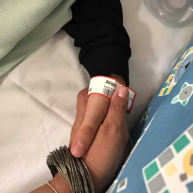 A close up of Abi's mum holding her hand while she's in hospital.