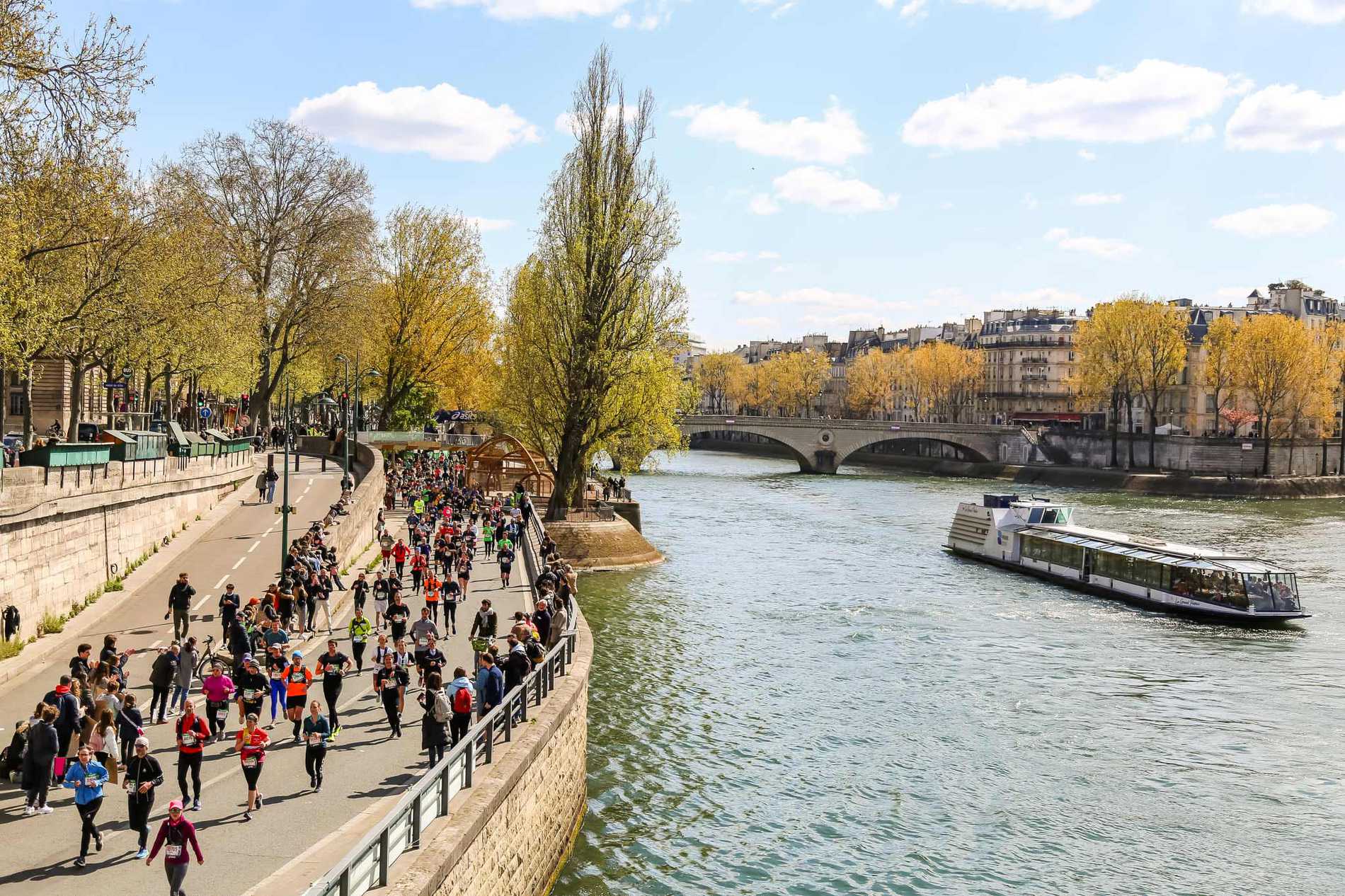 A crowd of runners making their way along the banks of the River Seine.