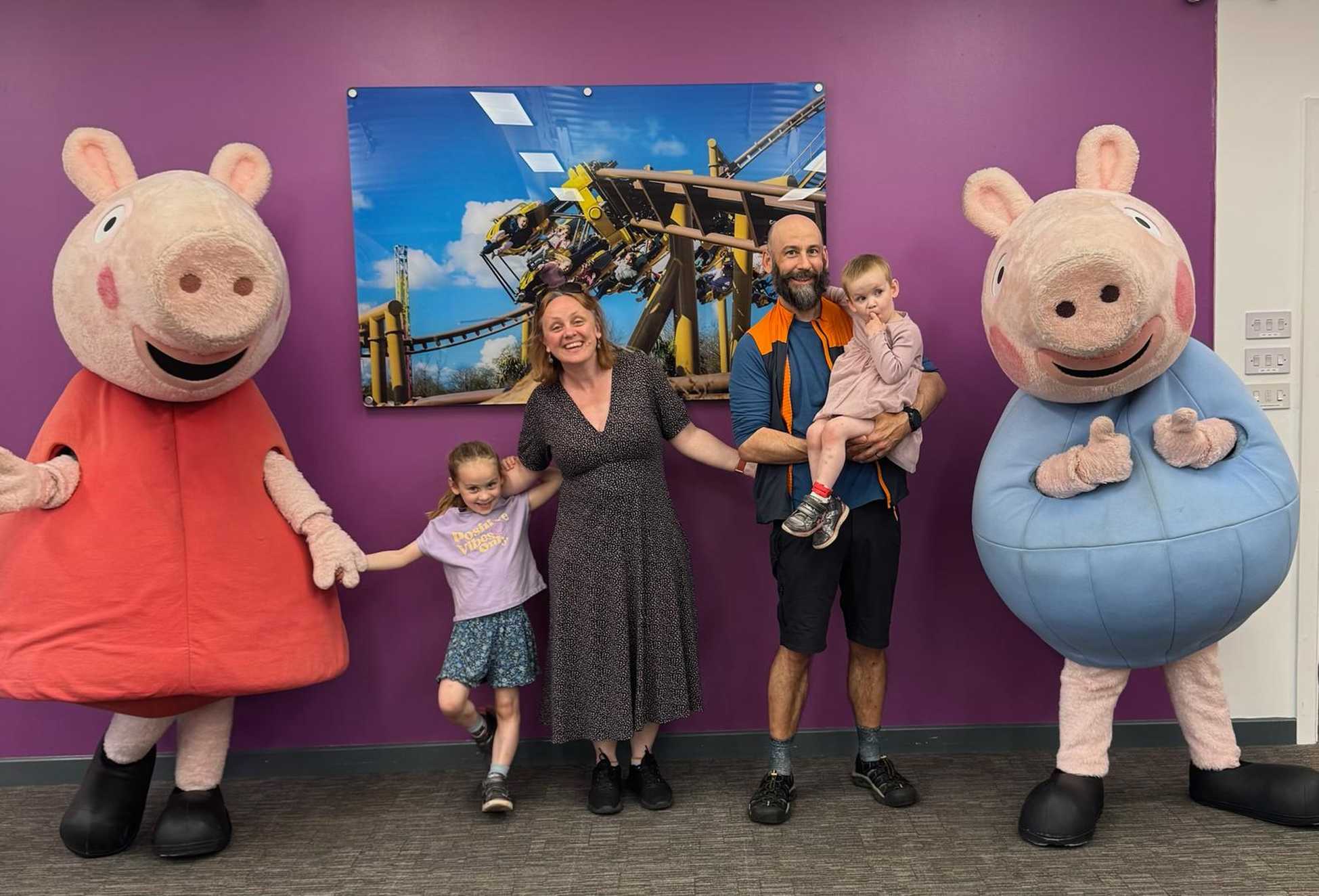 On the left, Peppa, the main character from Peppa Pig is holding hands with Annalena’s sister, who stands next to her mum, both smiling. Peppa is smiling, wearing a red dress. To their right, Annalena’s dad is holding her smiling.