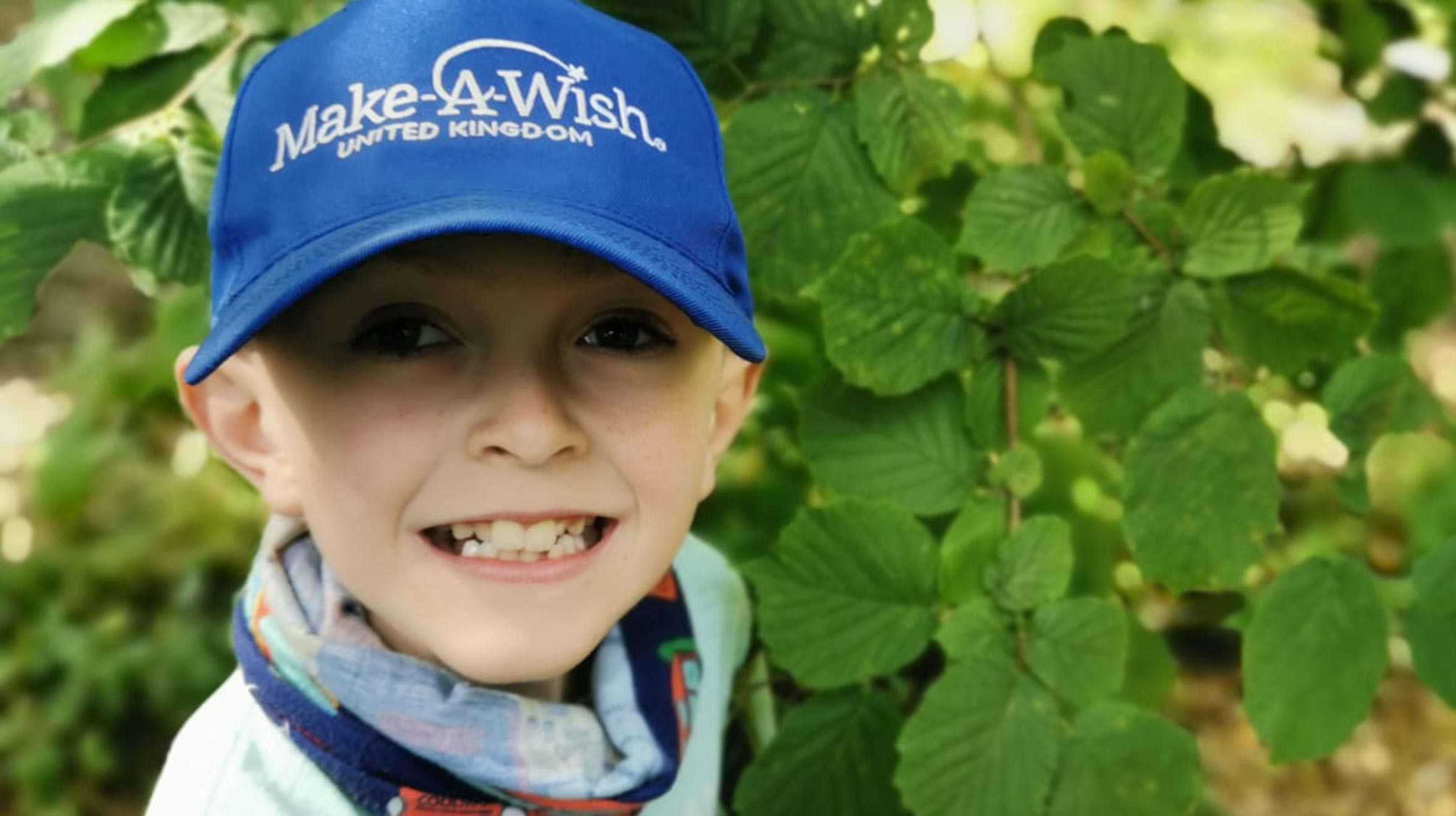 Caden smiling and inspectting the leaves of a plant