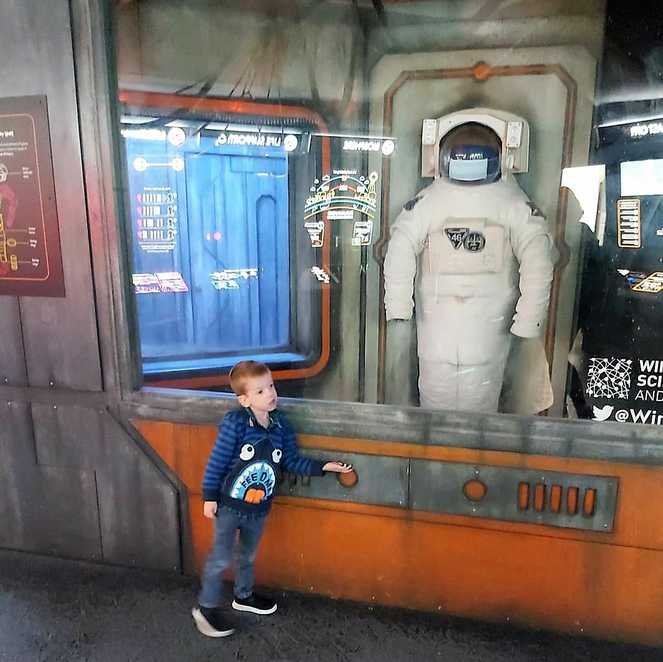 Aiden standing in front of a display of a space suit at the Winchester Science Museum.