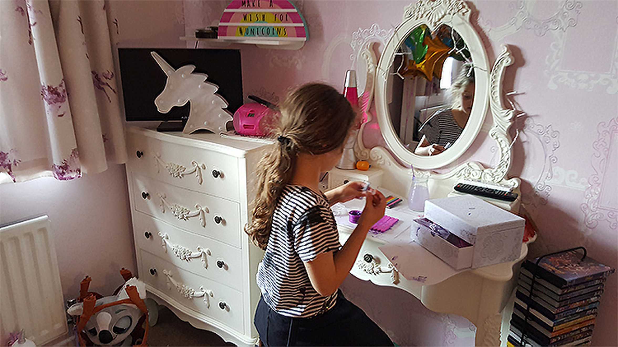 Jade sitting by the dressing table in her new unicorn-themed bedroom