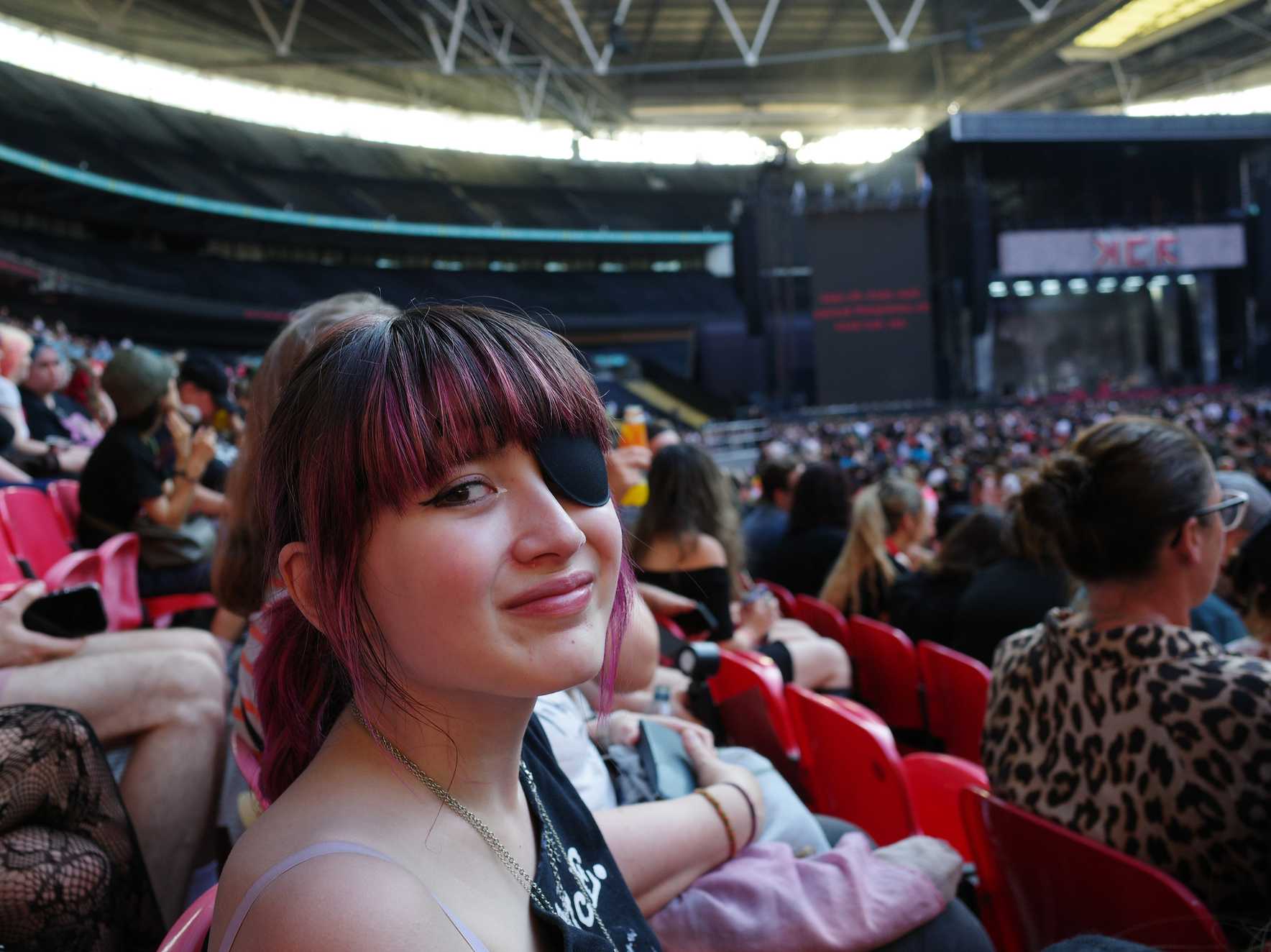 Phoebe smiles in the crowd at Wembley Stadium, with the stage over her shoulder