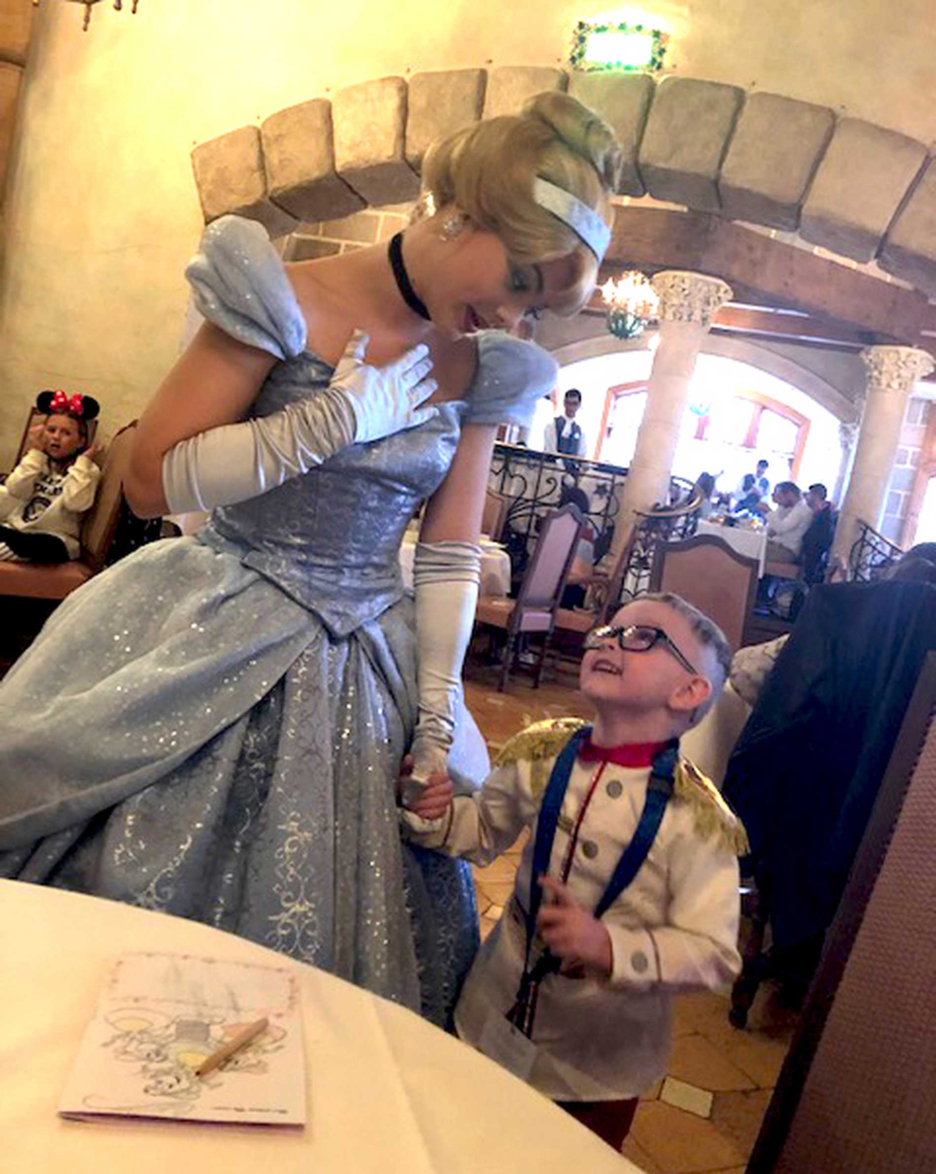 Patrick, dressed as a prince, holding the hand of a Disney princess.