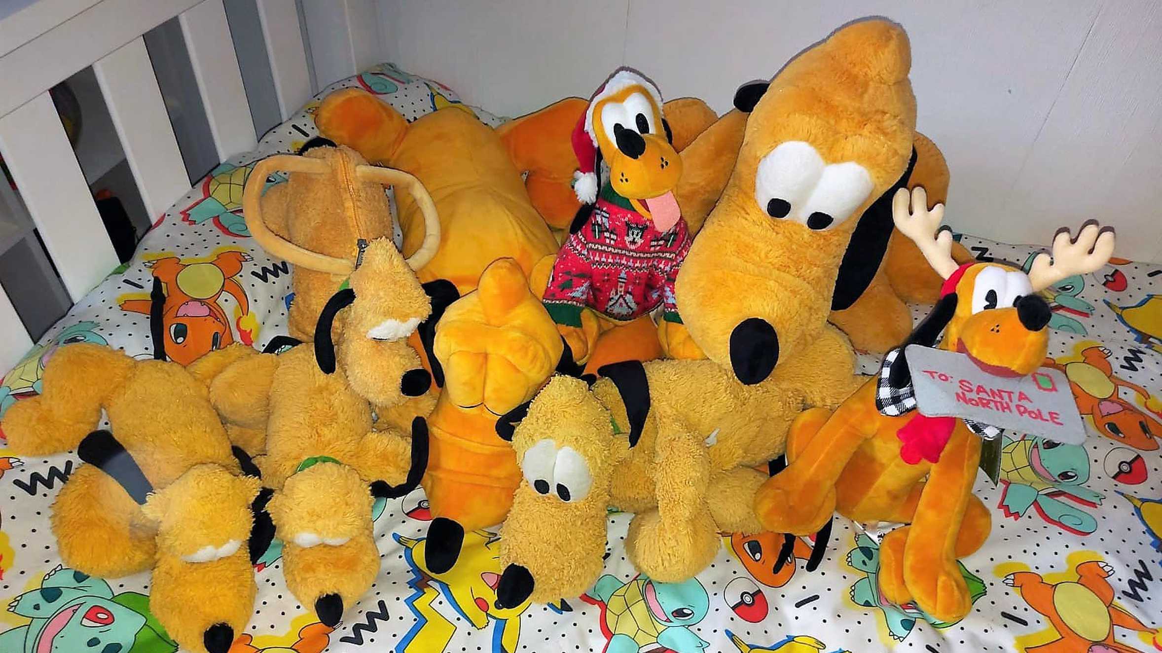 Alfie's large collection of Pluto soft toys on his bed at home.