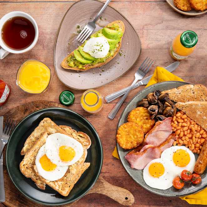 A table filled with an assortment of breakfast foods, including fruits, pastries, and beverages.