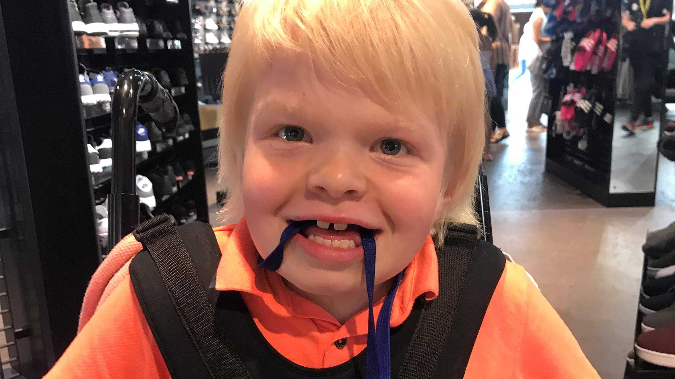 Jack sitting in his wheelchair in a shop, with big smile on his face.