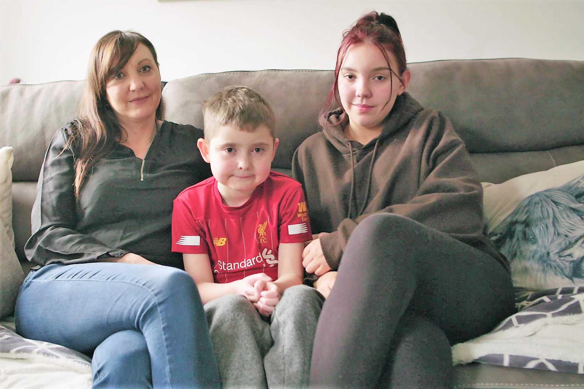 Wish child, Archie sitting on the sofa in his Liverpool shirt, with his mum and sister.