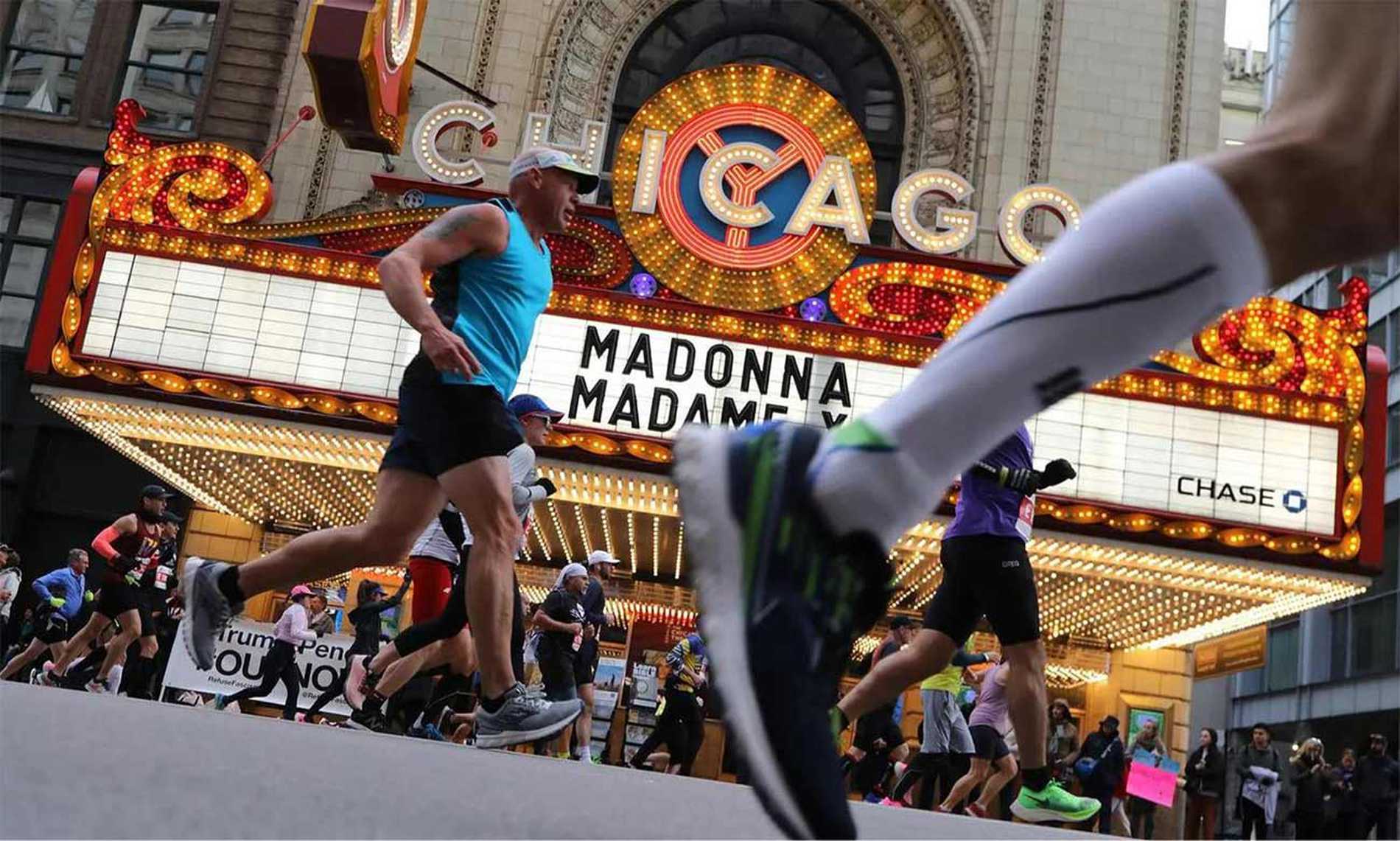 A close up of a runner's foot pounding against the road as they pass by the iconic Chicago Theatre.