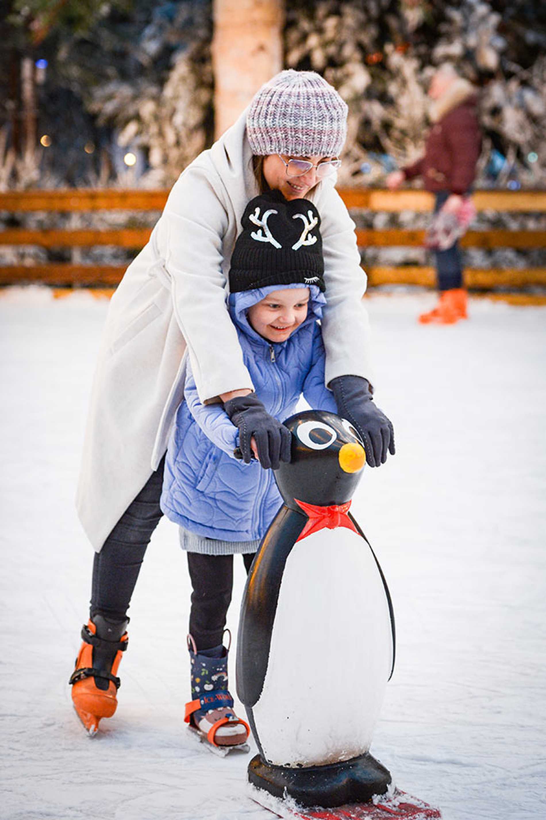 Julia holding onto a penguin stabiliser while she ice skates with mum.