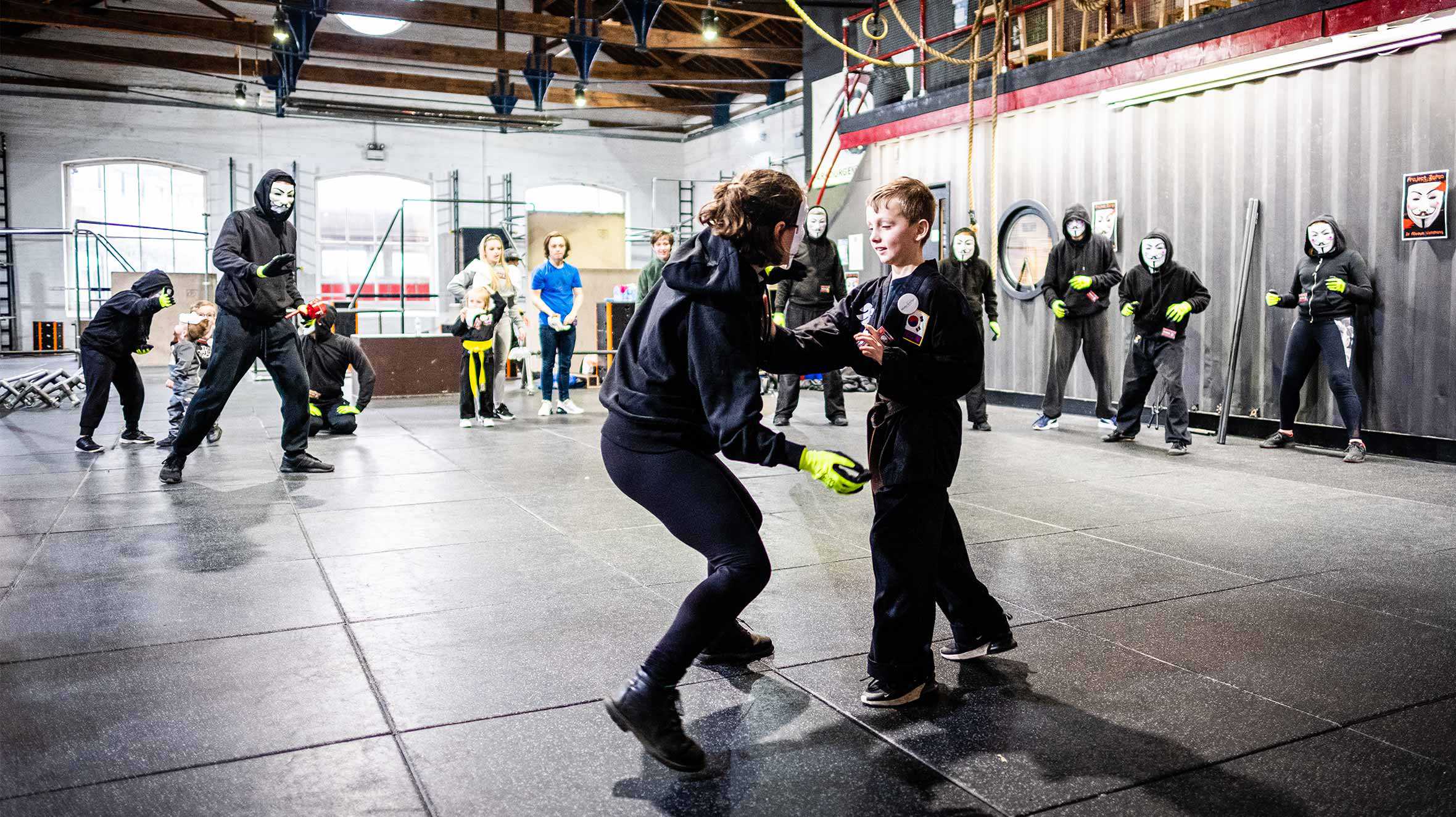 Kian sparring with another ninja while other watch on in the background.