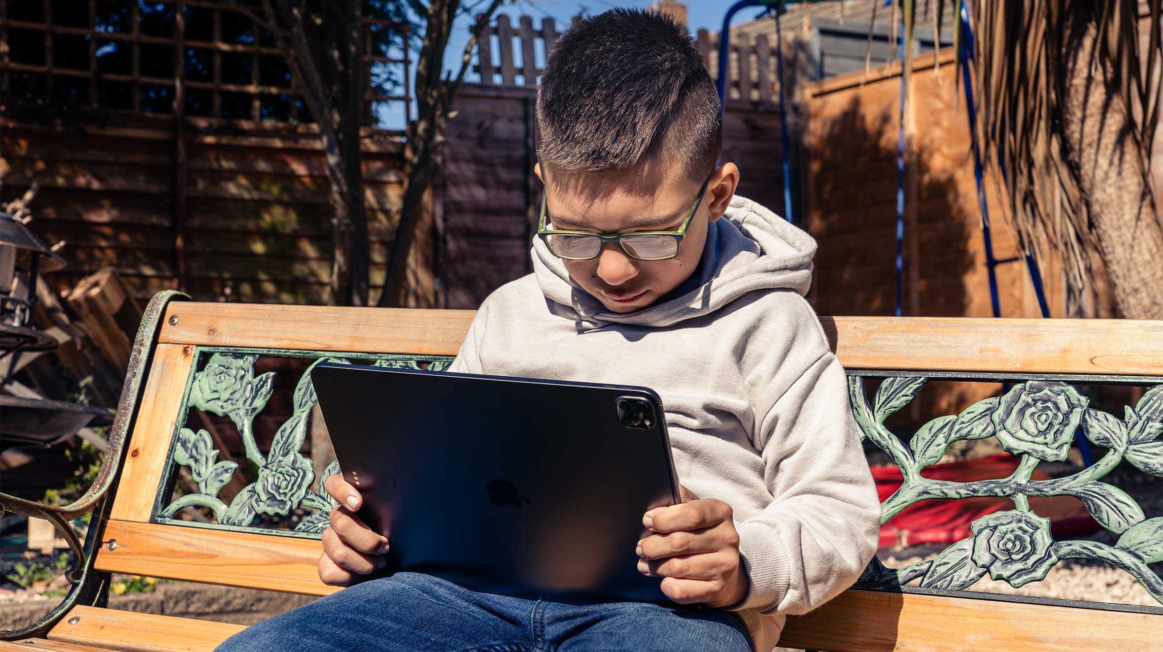 Harvie, watching a video on his iPad while sitting on a bench in his garden.