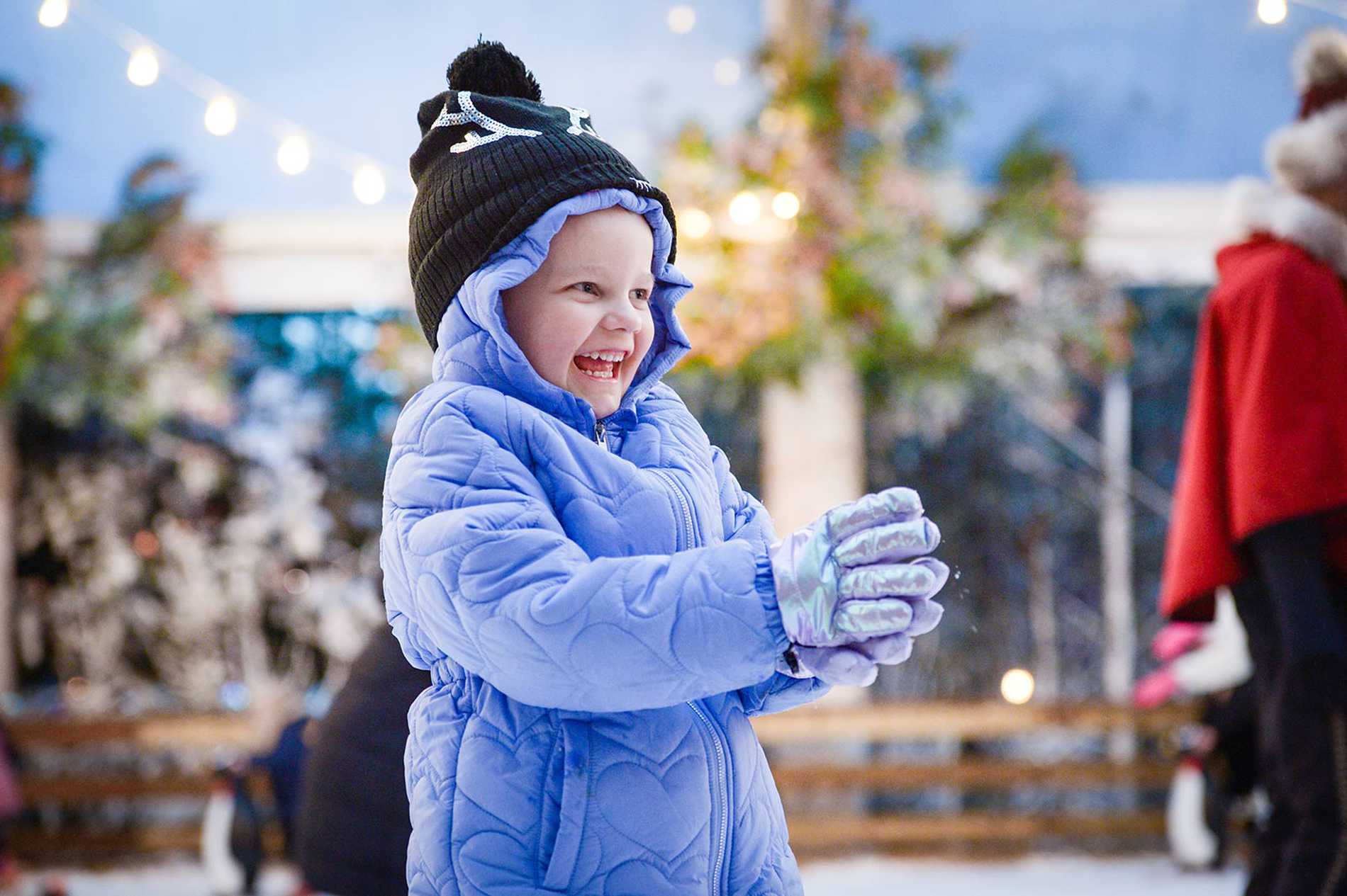 Julia smiling in her blue padded snowsuite and gloves.