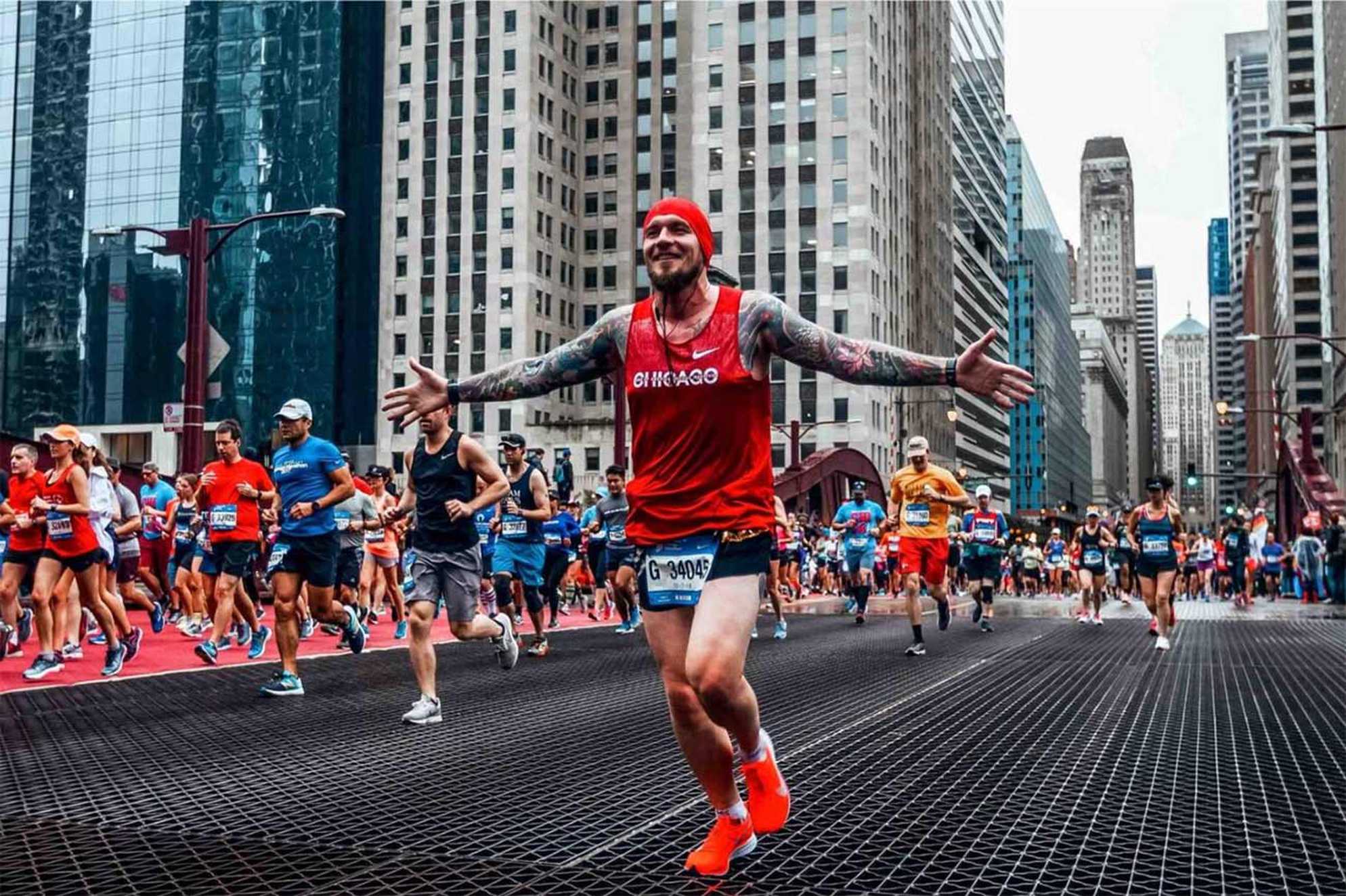 A runner with his arms in the air as he passes through the city streets during the Chicago Marathon.