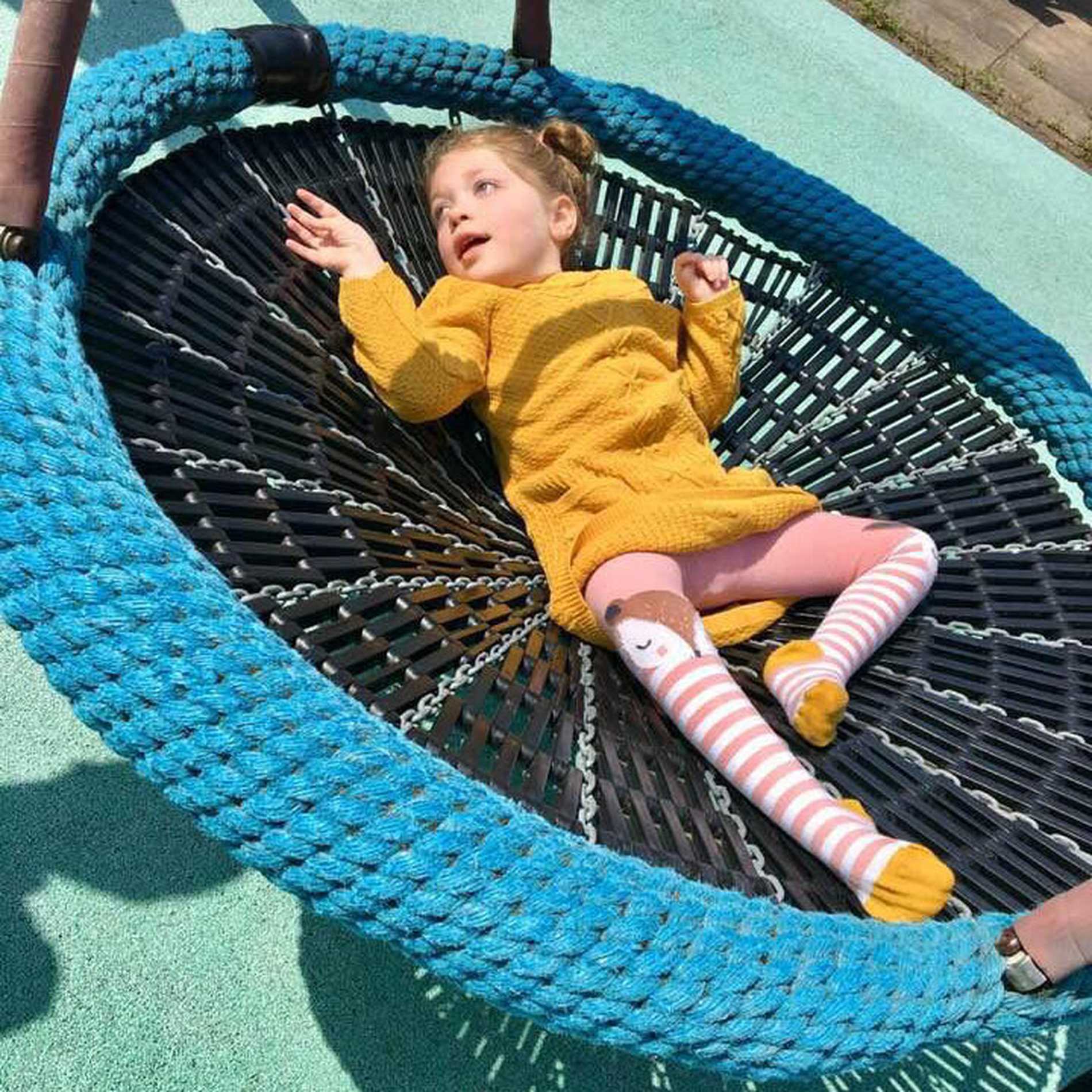 Aubree enjoying being pushed on a swing in the playground