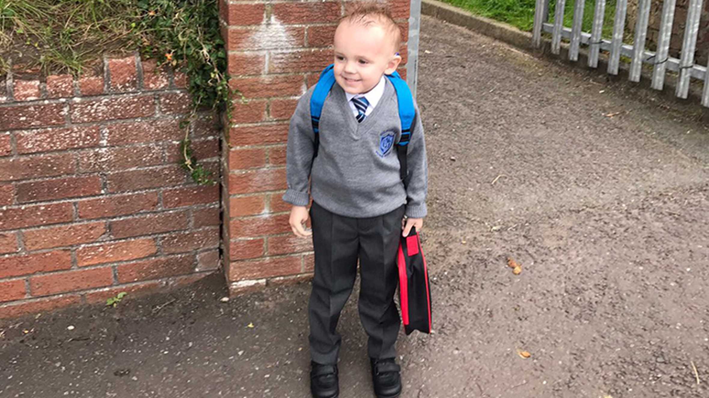 A smiling Zak wearing his grey school uniform.