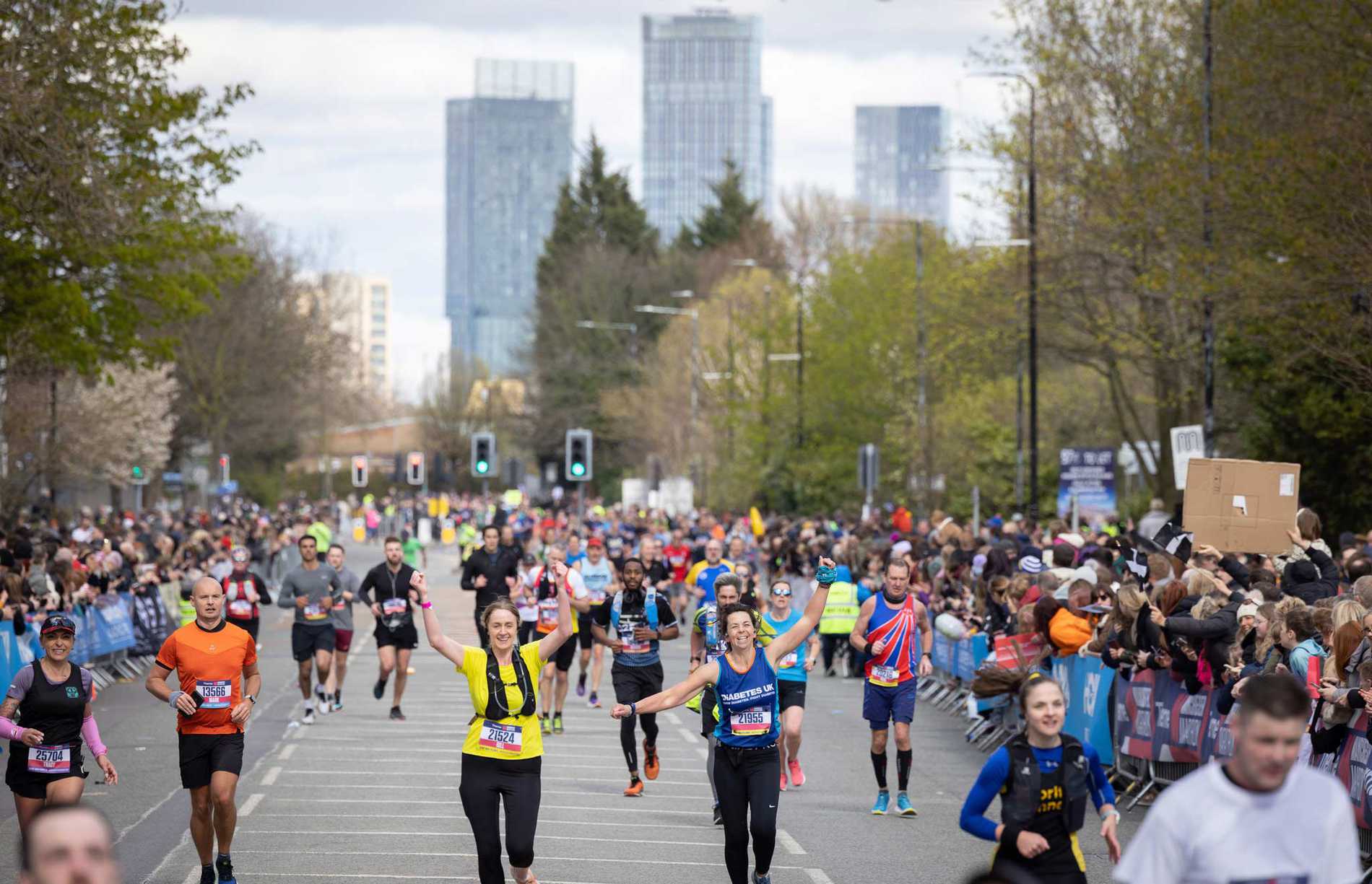 Manchester Marathon runners with the city's skyline in the background.