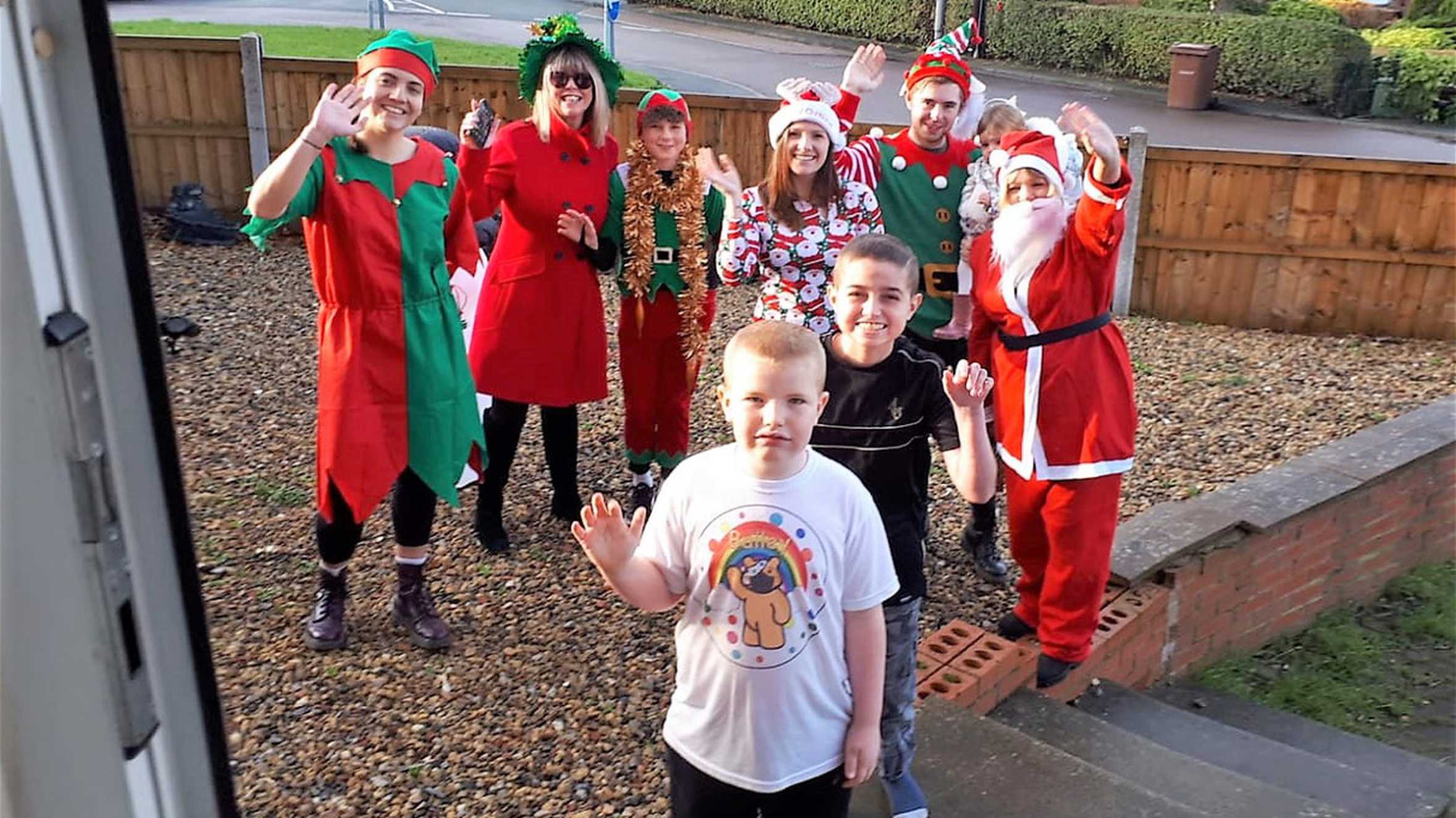 Adam and his brother Bailey, standing in front of their house with Father Christmas and his elves.