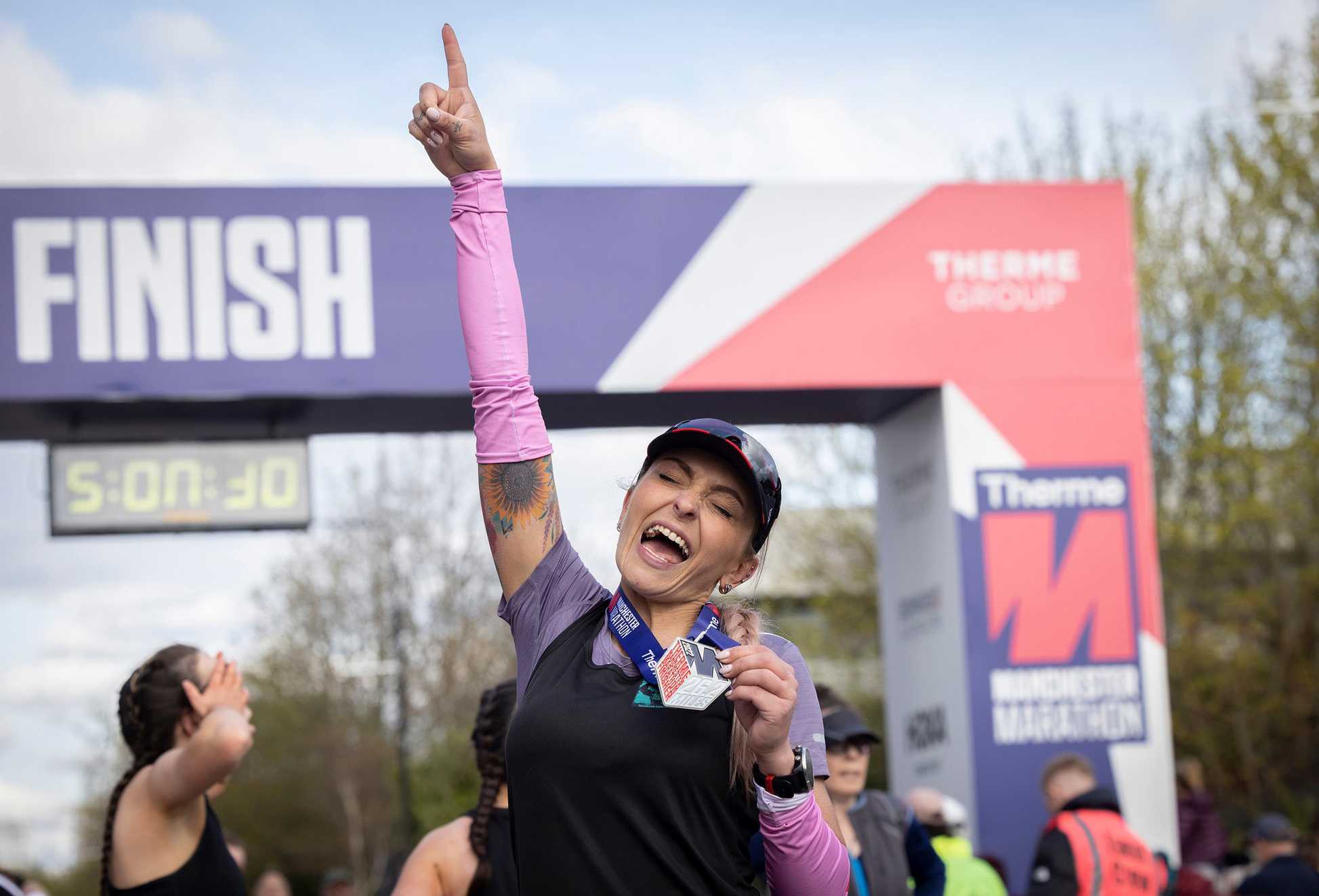 A happy participant punches the air after completing the Manchester Marathon.